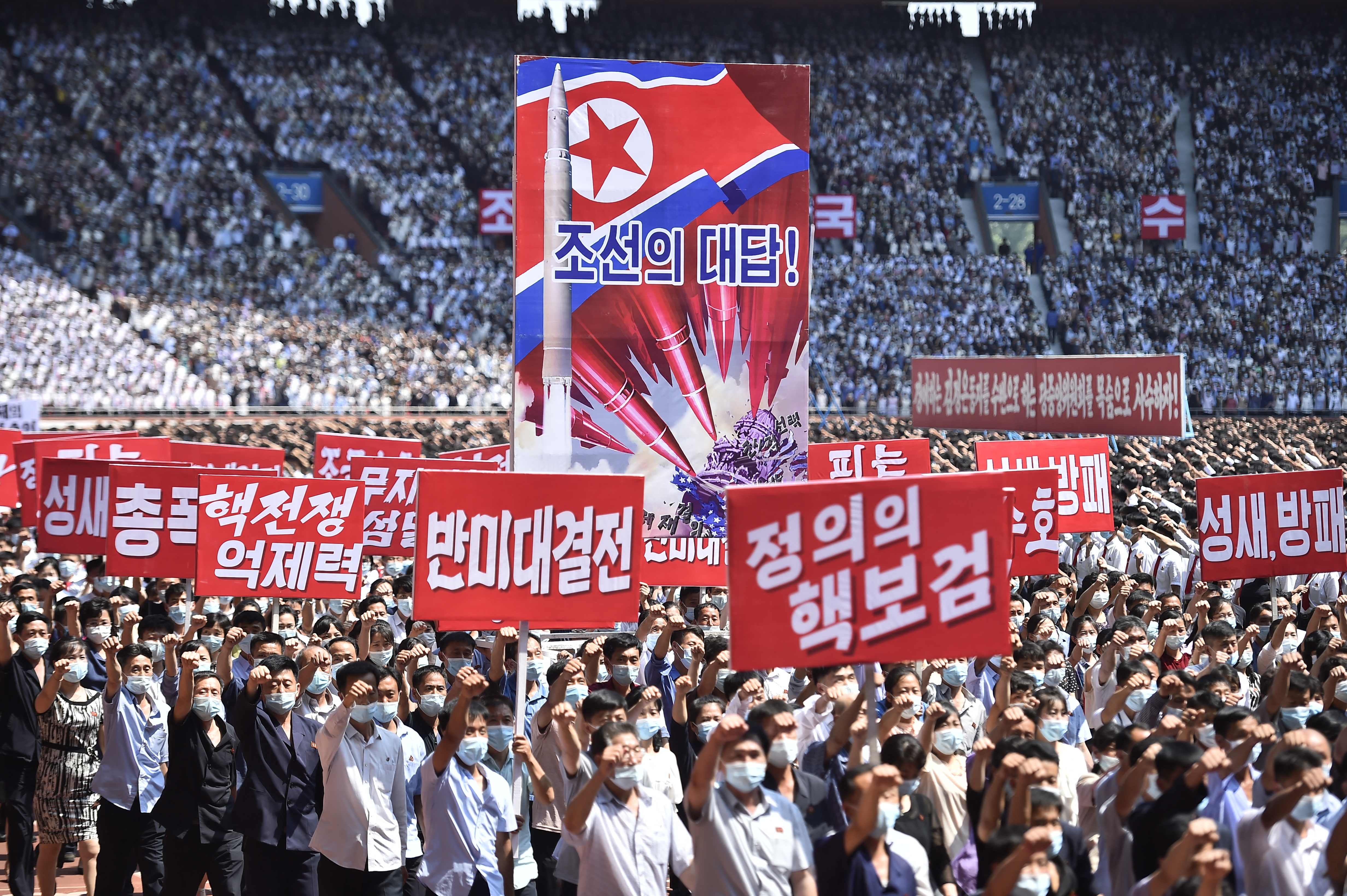 People in Pyongyang hold banners that read "answer of DPRK", "nuclear war deterrent", "anti-US confrontation" and "the nuclear treasured sword of justice" during a mass rally