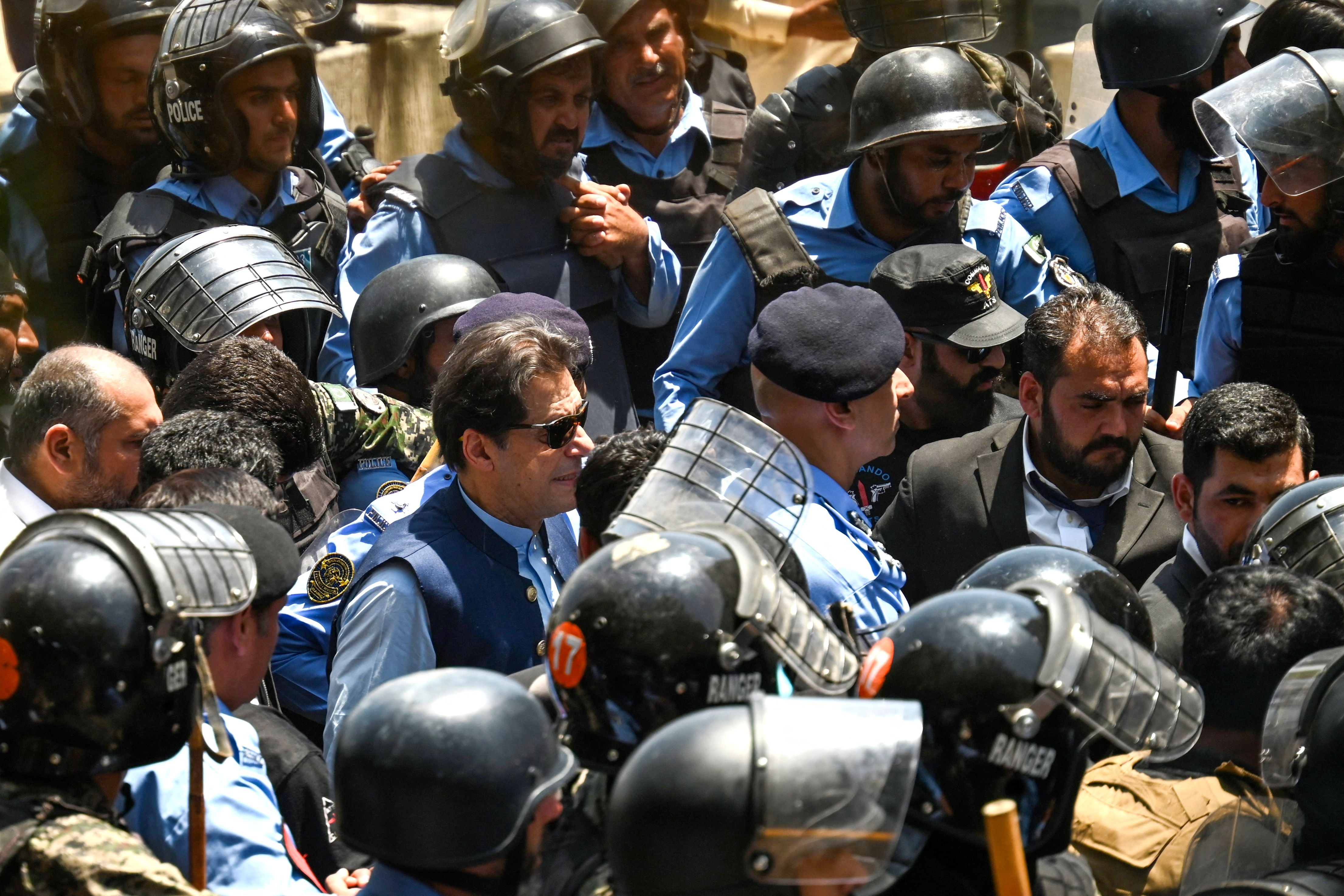 Policemen escort Pakistan’s former prime minister Imran Khan (C) as he arrives at the high court in Islamabad