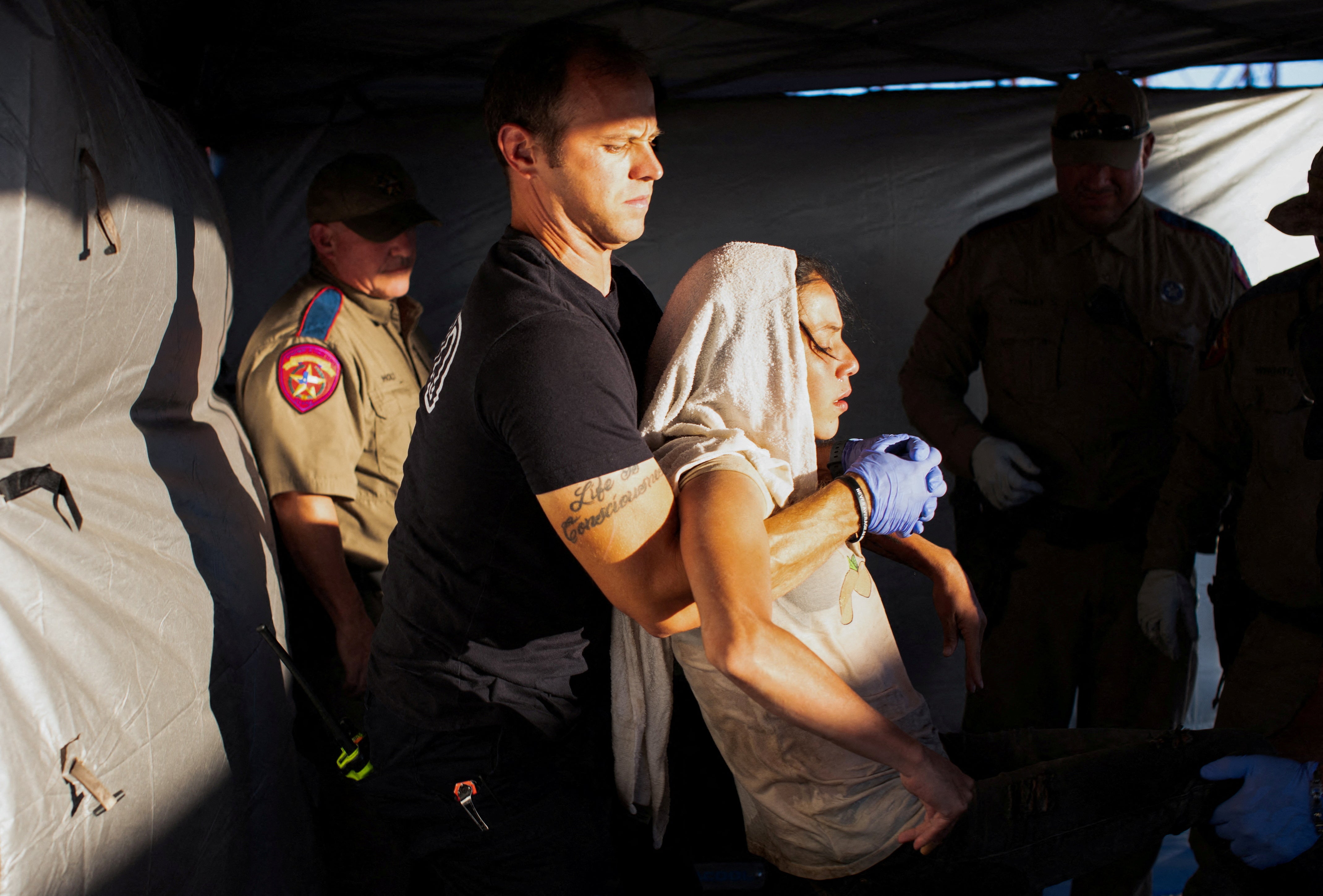 Firefighter EMT William Dorsey lifts a migrant woman suffering from heat exhaustion onto a stretcher in the border community of Eagle Pass, Texas on June 26, 2023