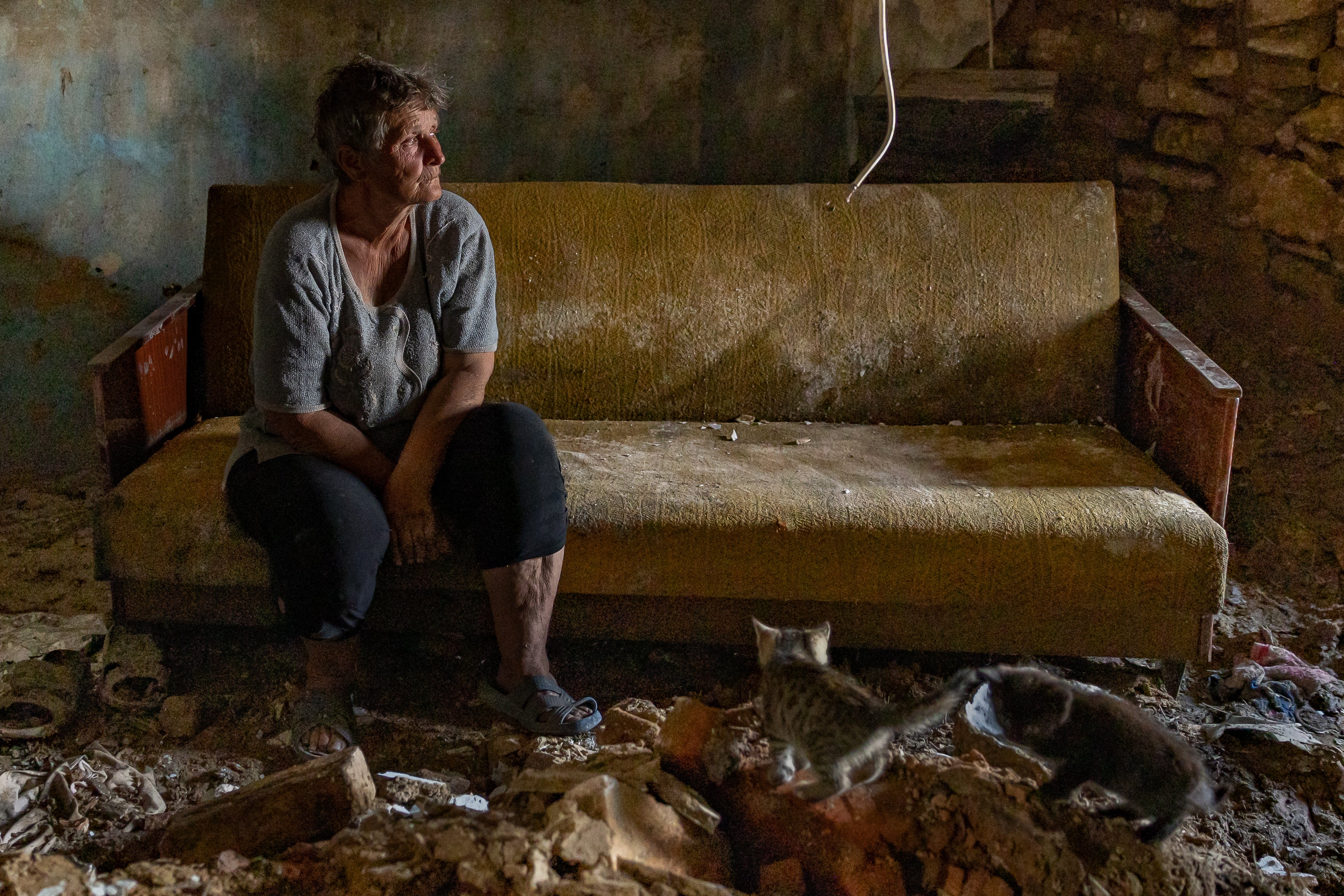 Olha sits by piles of brick which is all that remains of her living room wall in Mykolaiv