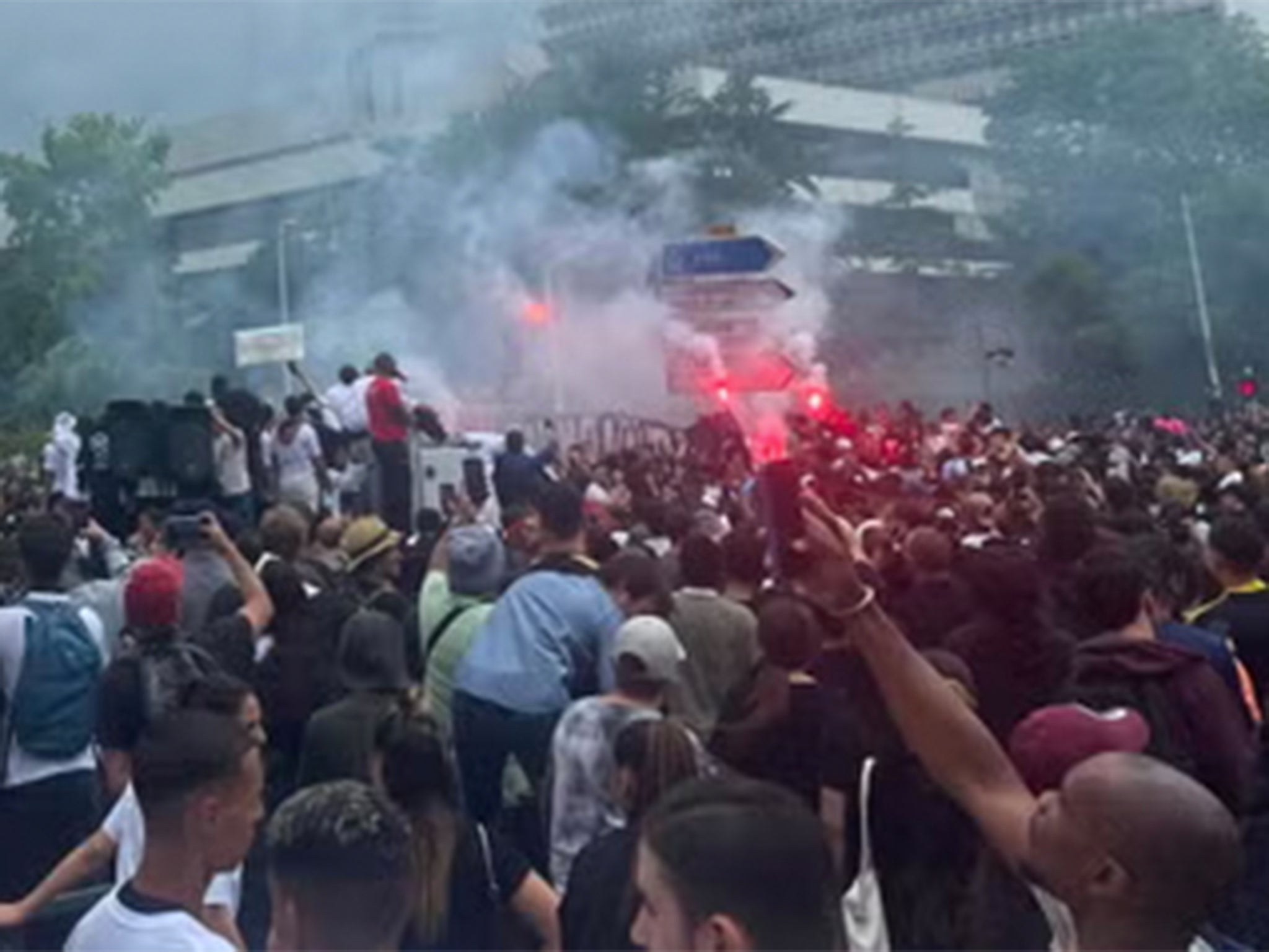 We all roar in support as we watch Nahel’s mum, Mounia, stand on the roof of the van outside the courts, holding a flaming flare in her hand