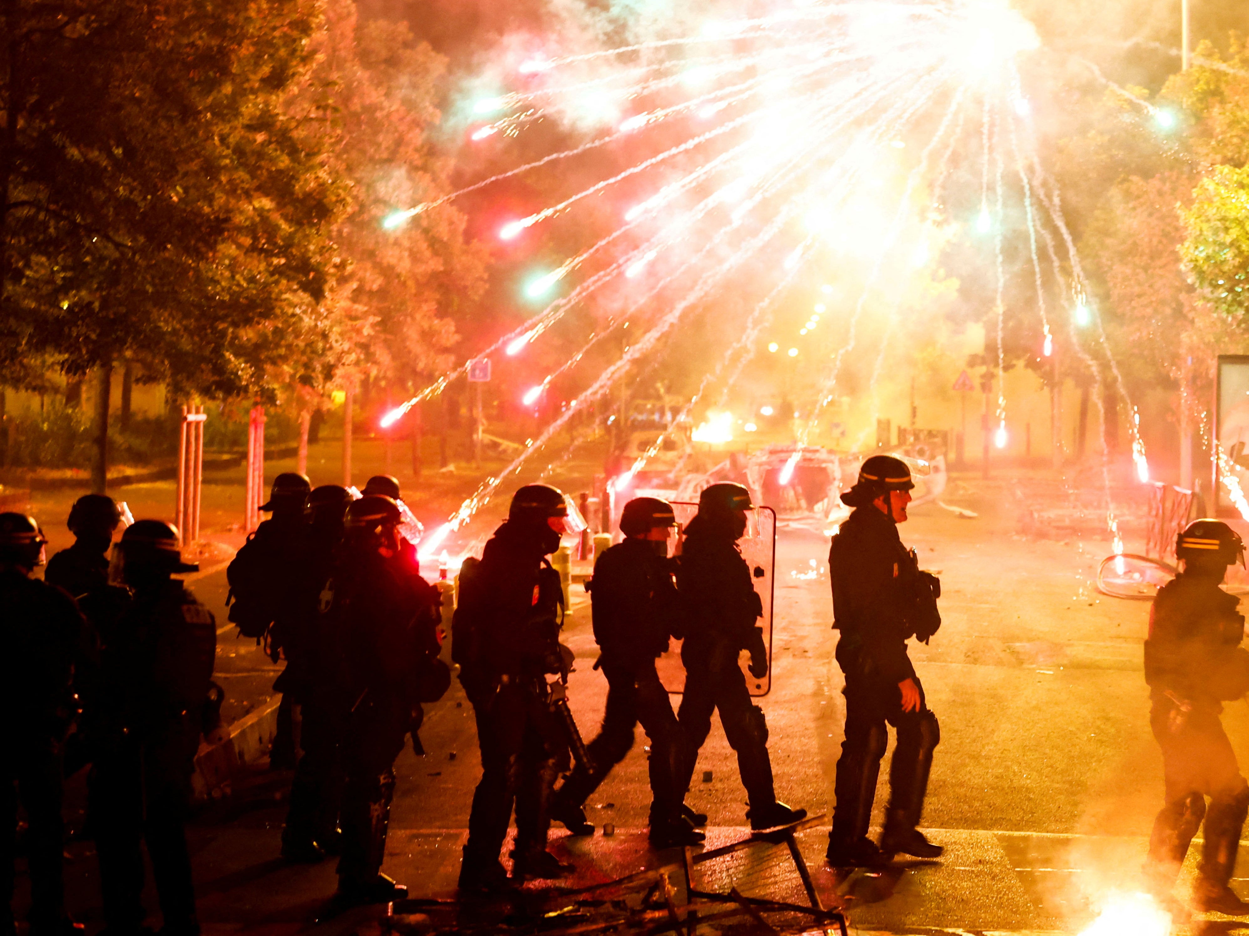 French police stand in position as fireworks go off during clashes with protesters in Nanterre