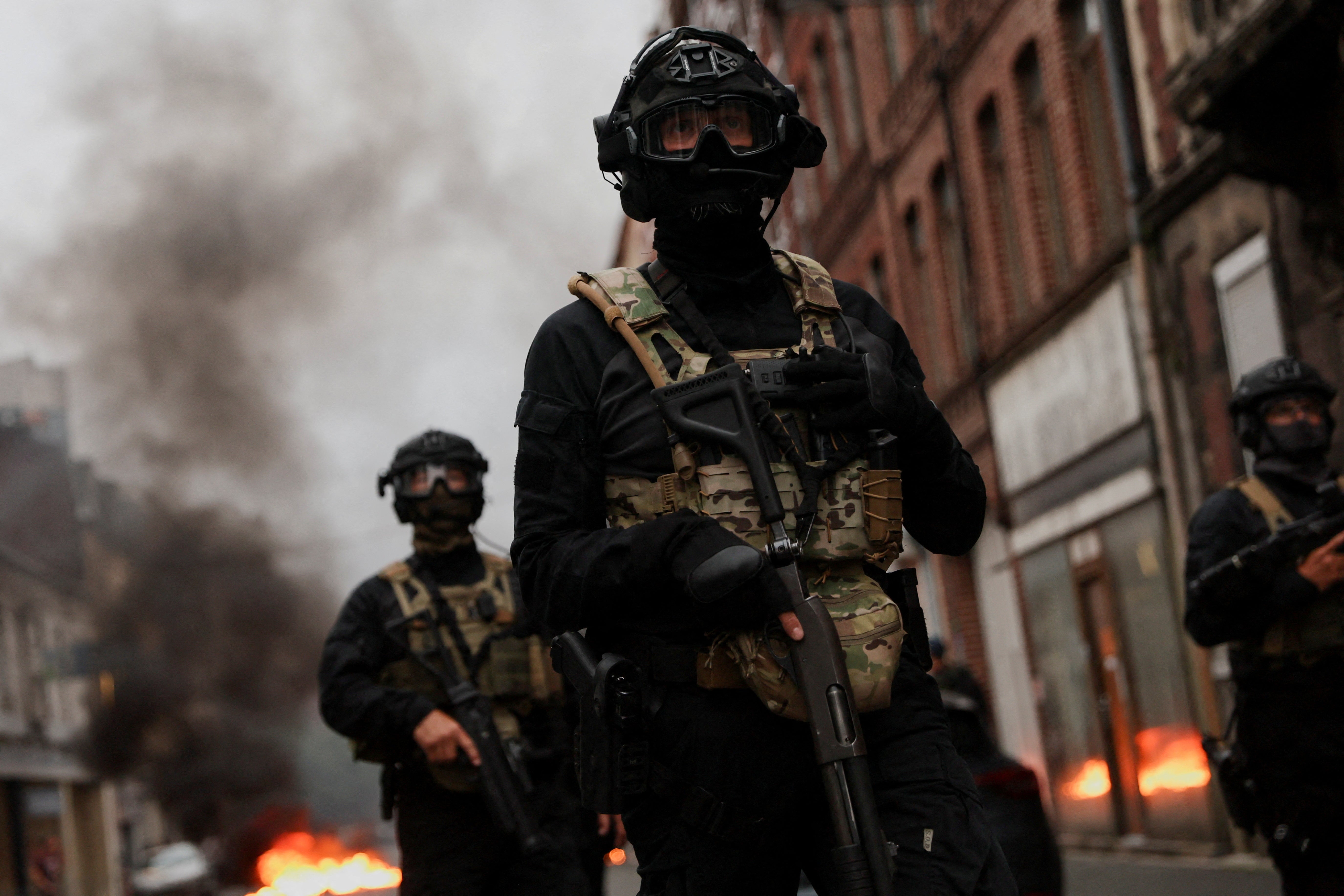 Officers stand guard during riots following the death of Nahel