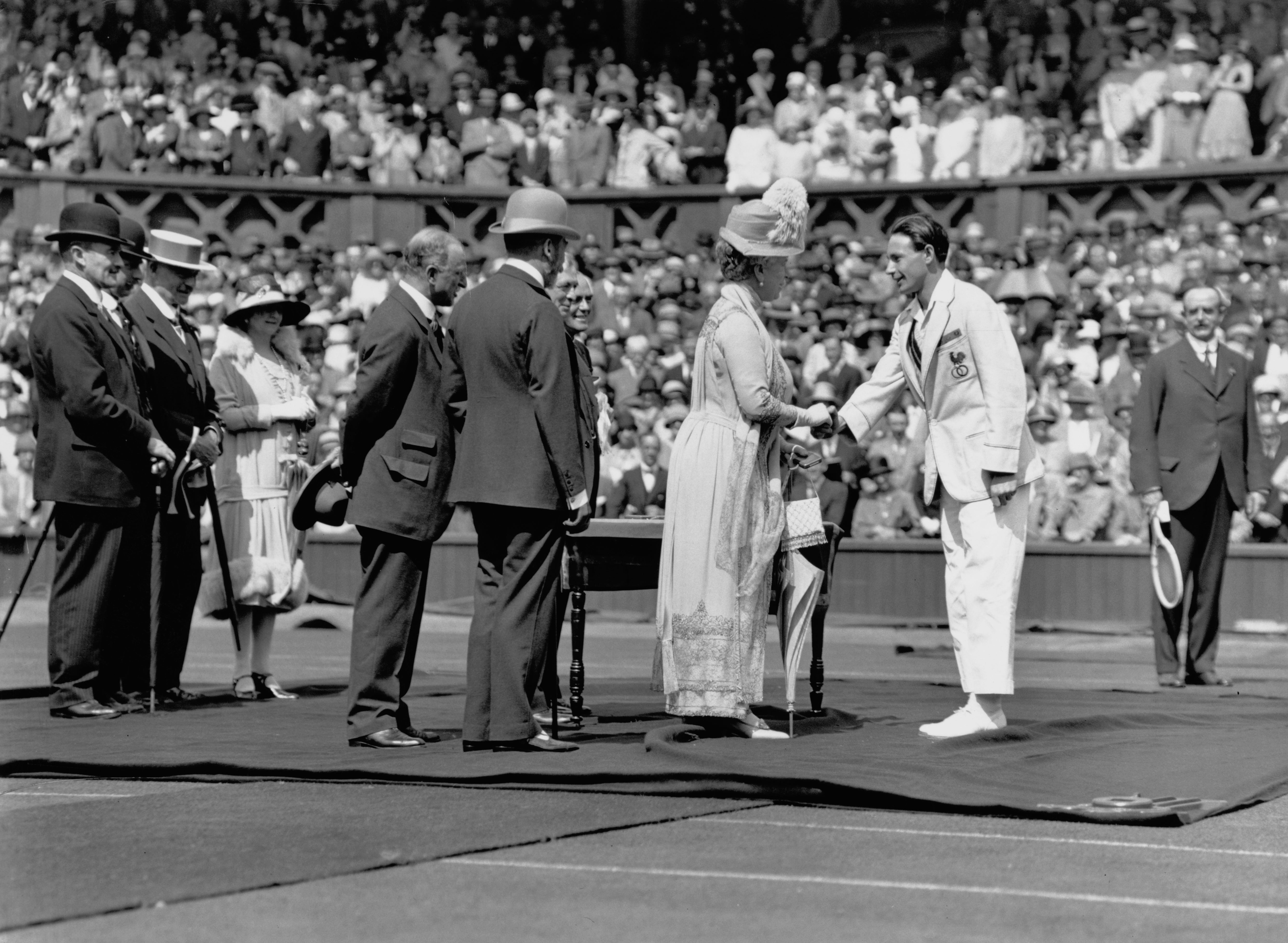 Wimbledon tennis champion Jean Borotra (1898 - 1994) from France is presented to King George V (1865 - 1936) and Queen Mary (1867 - 1953), Queen Consort on Centre Court at the opening ceremony for the 1926 Jubilee Wimbledon Lawn Tennis Championship on 21st June 1926