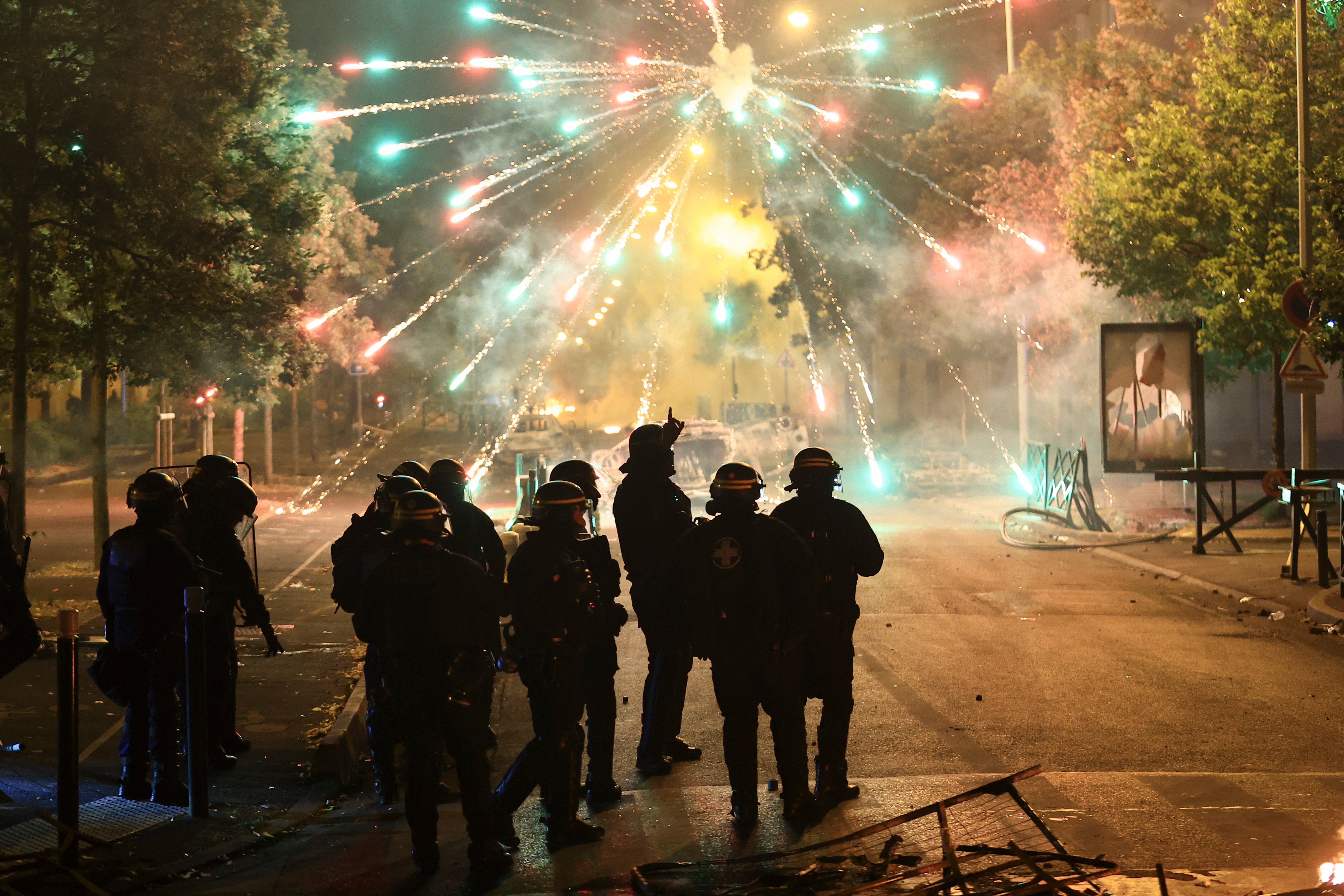 Police stand amid firecrackers on the third night of protests