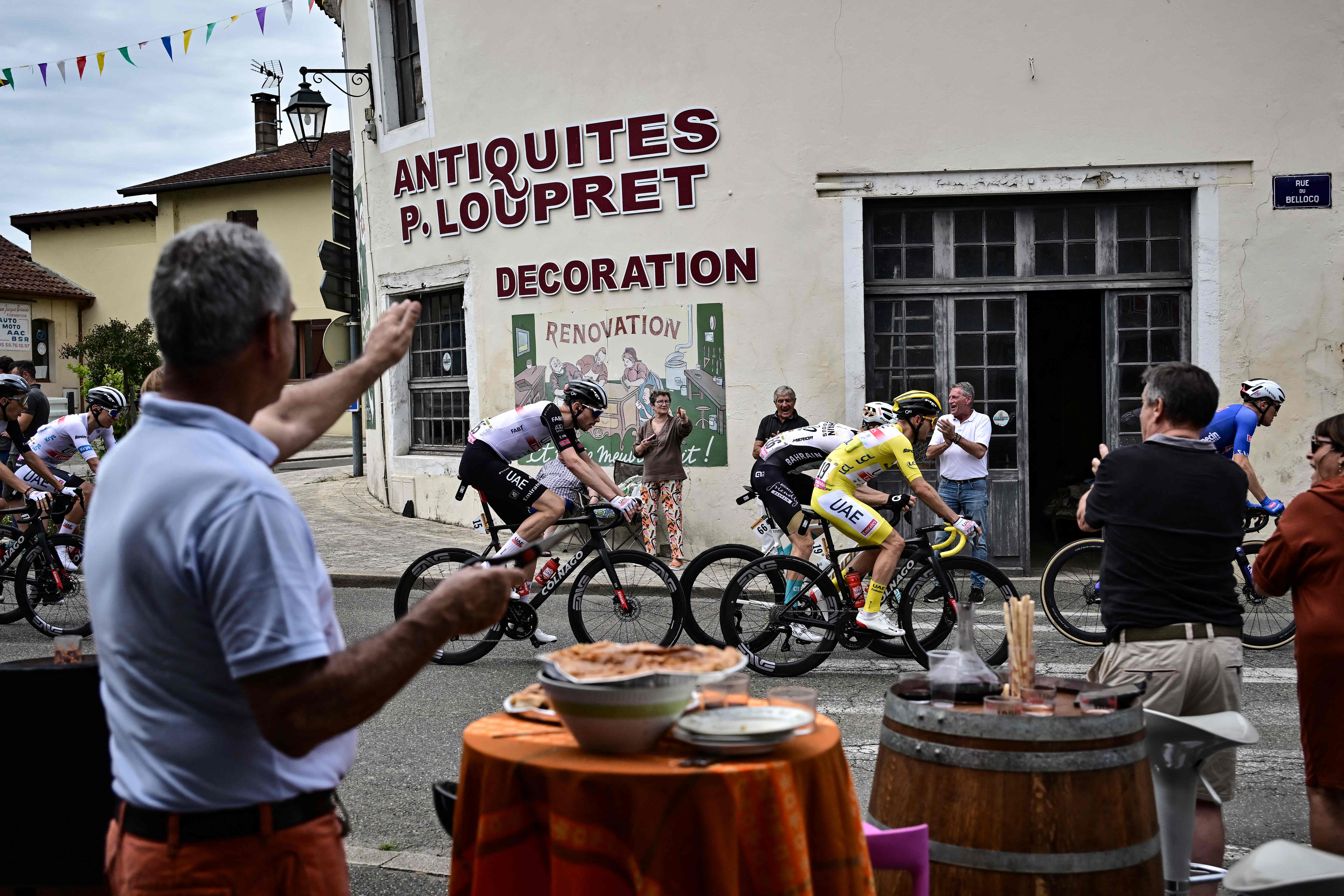 A spectator cheers from his buffet set up along the roadside as UAE Team Emirates' rider Adam Yates, wearing the overall leader's yellow jersey, cycles through Saint-Sever, during the 4th stage of the Tour de France between Dax and Nogaro, in southwestern France