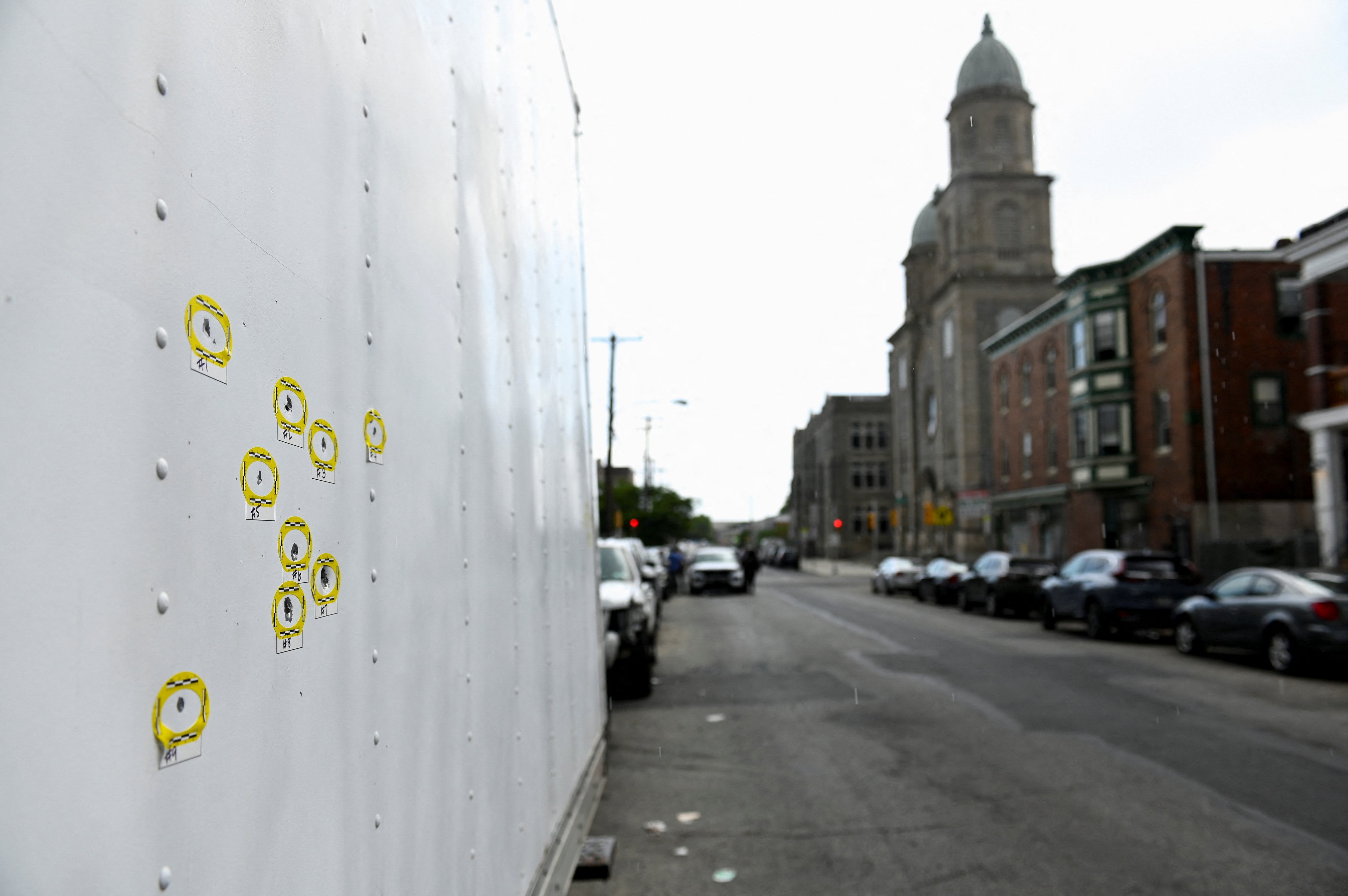 Bullet holes found on the side of a parked truck are marked as police officers work at the scene the day after a shooting in the Kingsessing section of southwest Philadelphia