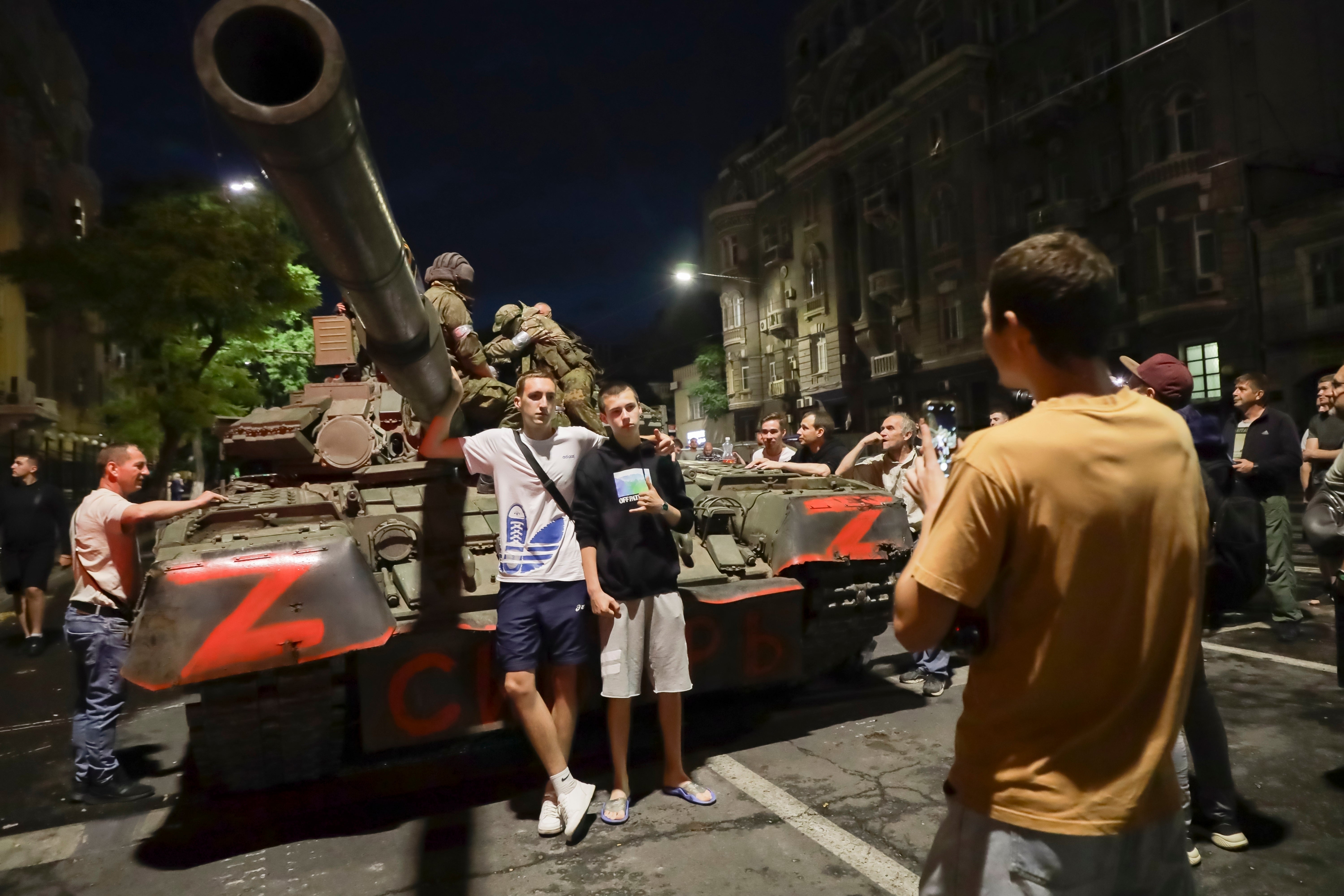 Wagner Group servicemen sit on top of a tank as local civilians pose for a photo in Rostov-on-Don