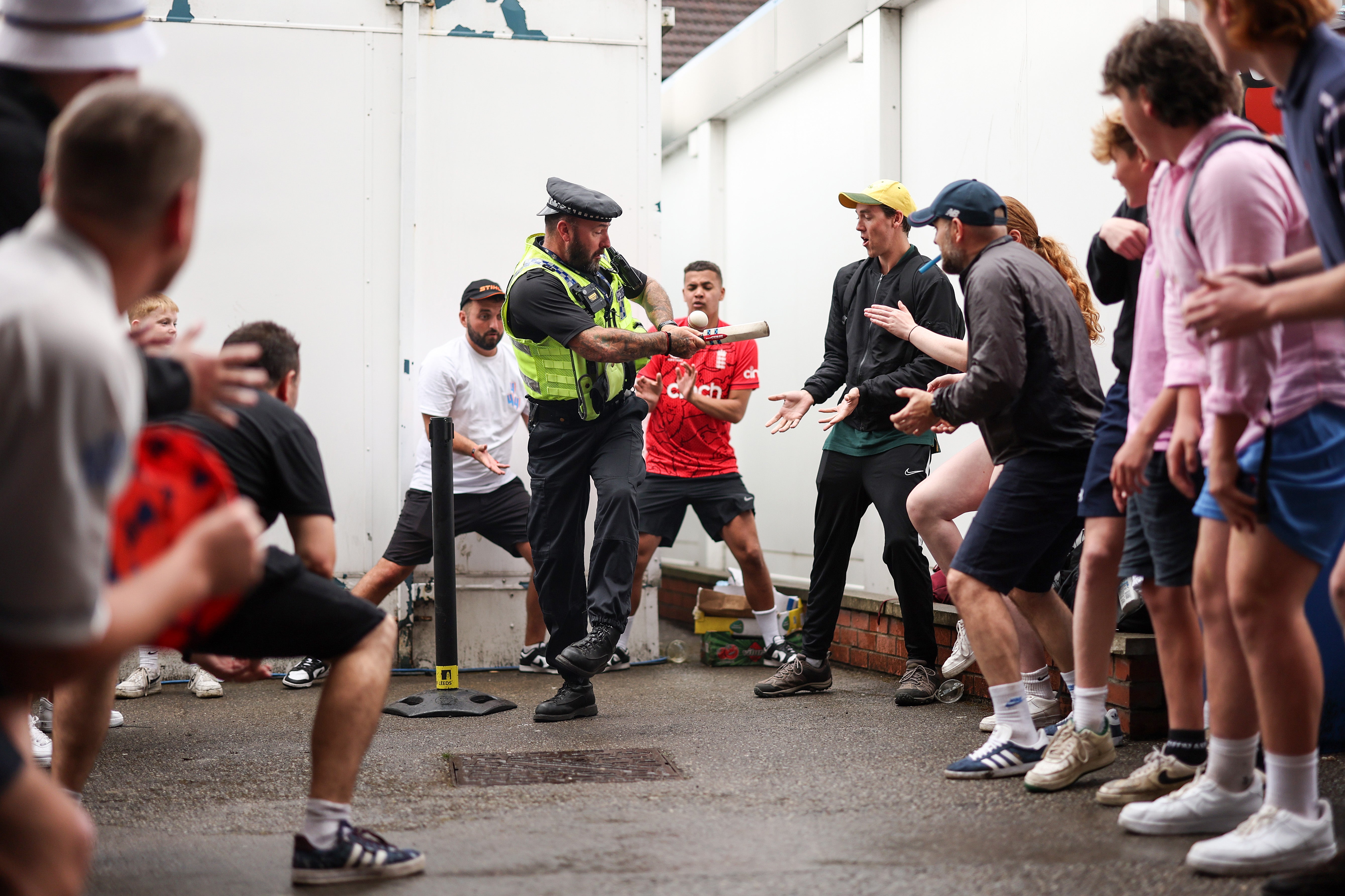 A police officer joins in on the cricket action with the rain delays postponing the game on the field