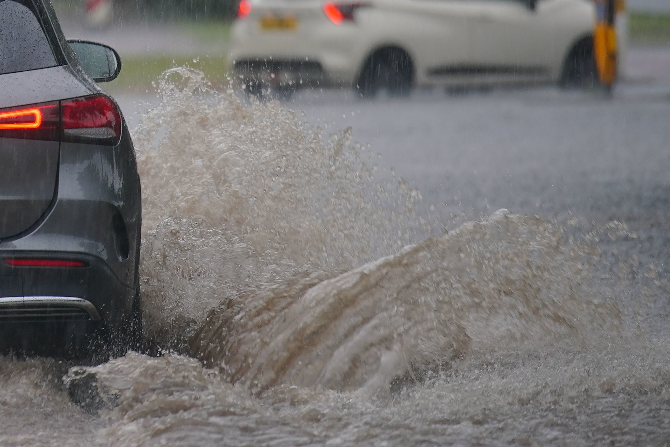 Cars drive through a flooded road after heavy rain in Speke, Liverpool