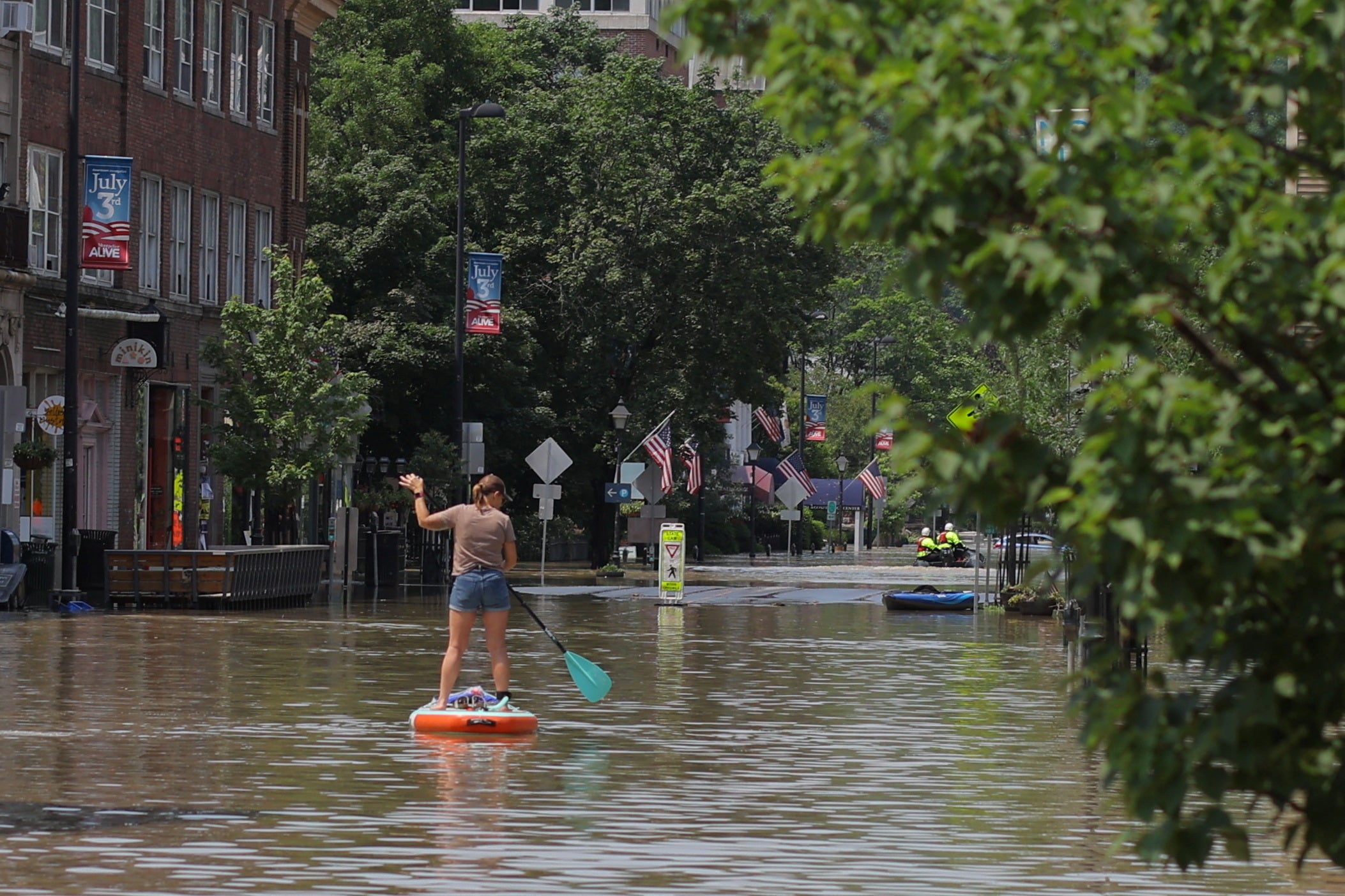 A woman rows a paddle board in a flooded area in Montpelier, Vermont on Tuesday