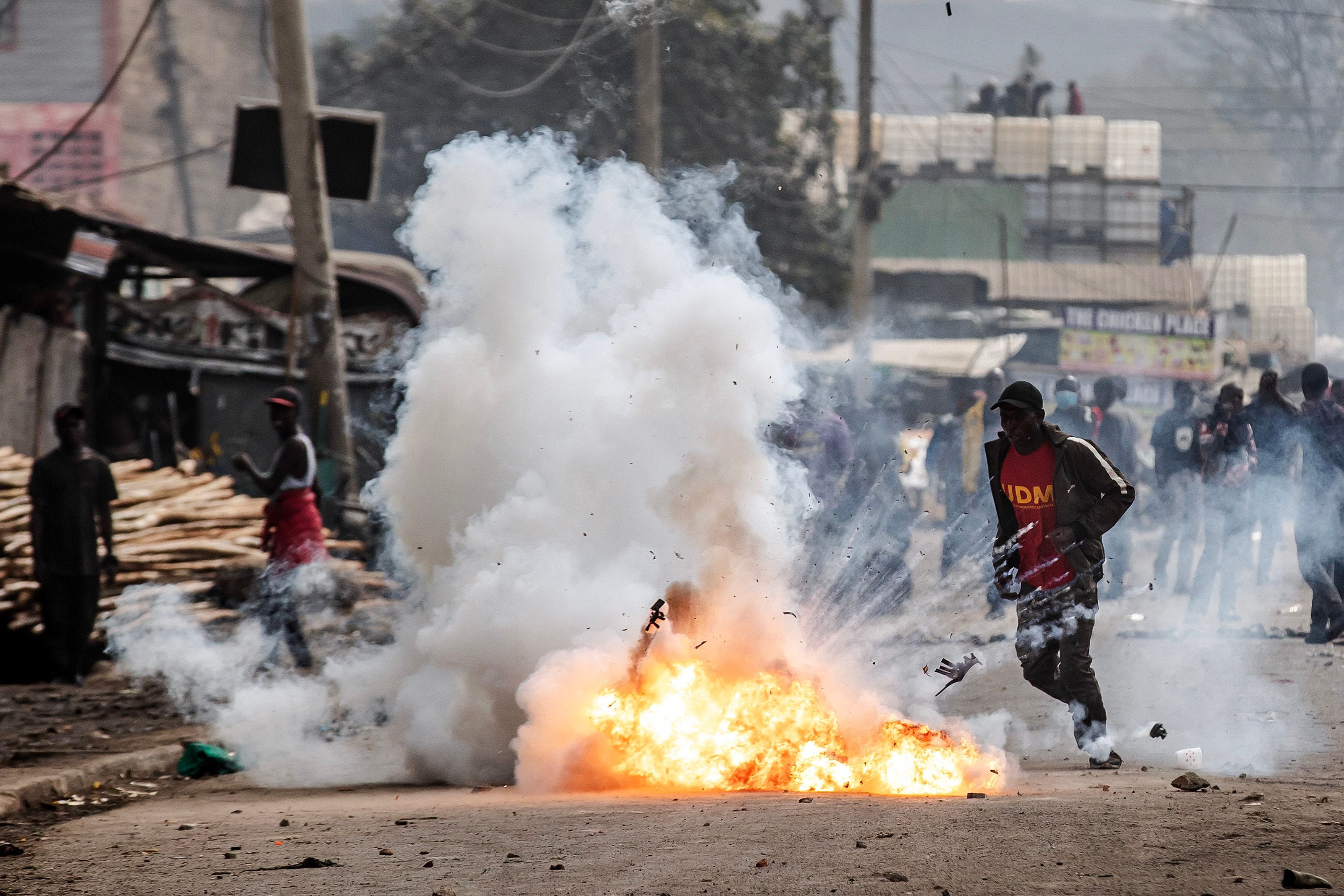 A Kenyan opposition supporter reacts as a teargas canister explodes in front of him during demonstrations with Kenya Police Officers in Nairobi, Kenya