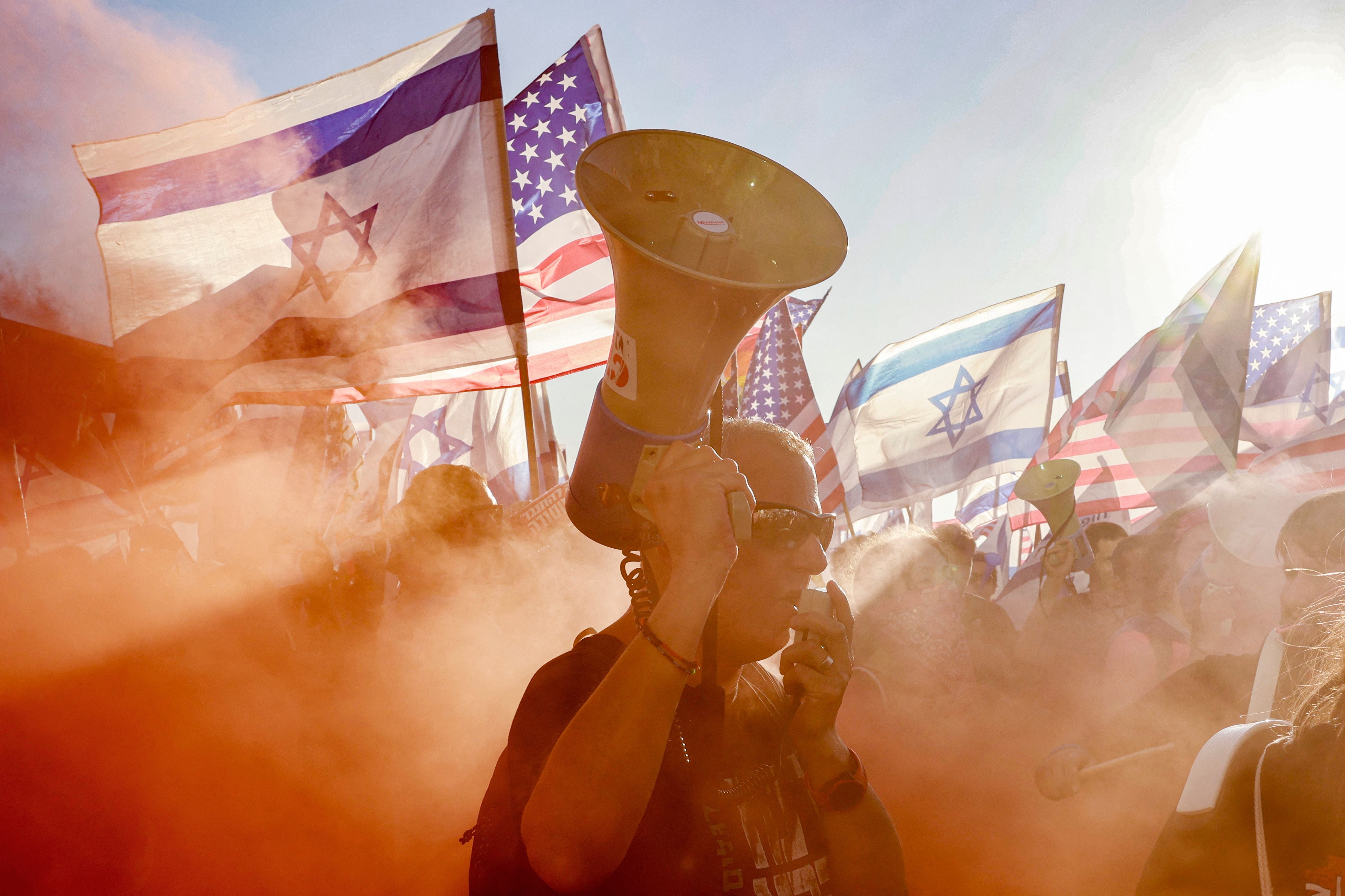 A demonstrator marches through the smoke of a flare during a protest against the Israeli government's judicial overhaul bill outside the US Embassy in Tel Aviv