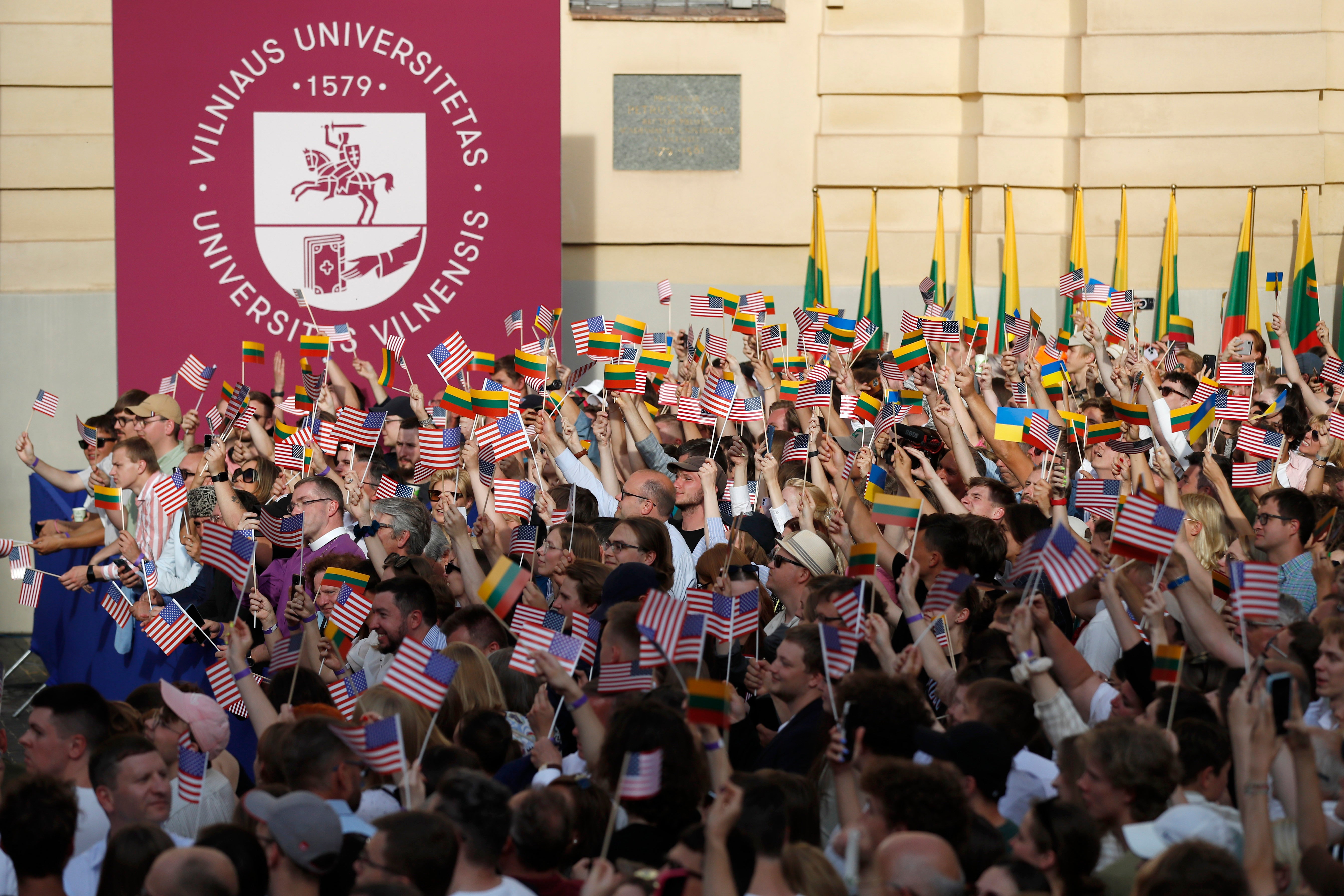 People wave American, Lithuanian and Ukrainian flags, as they wait for the arrival of United States President Joe Biden, at Vilnius University