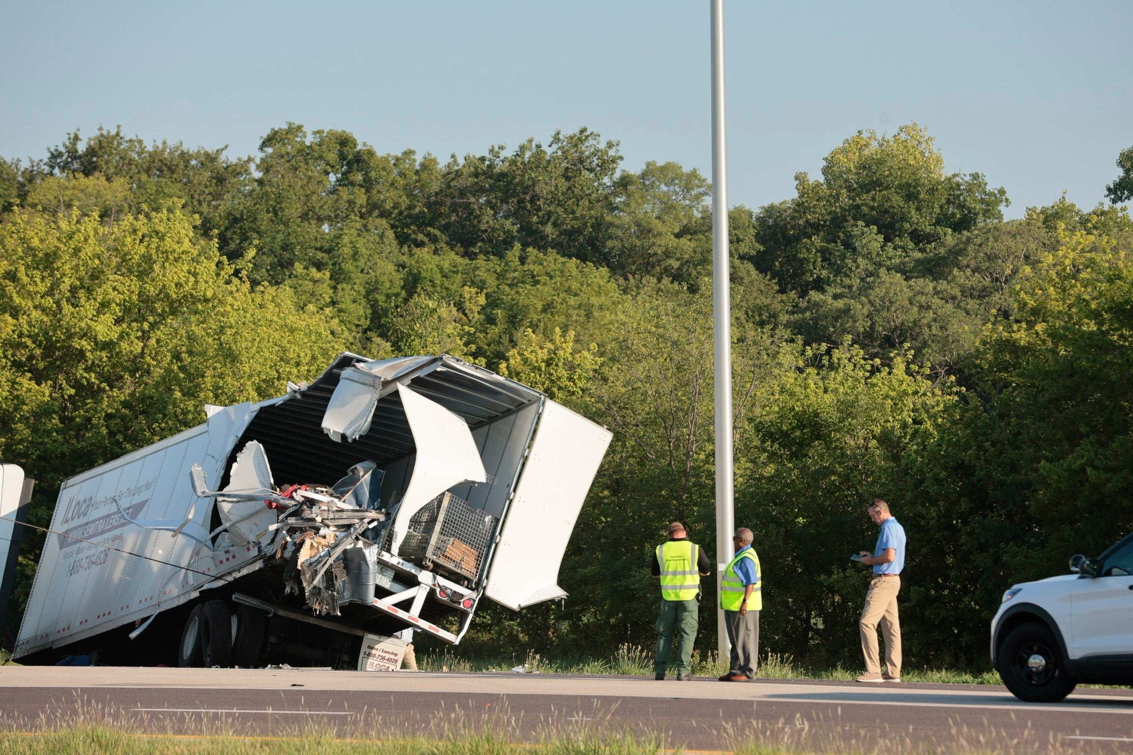 Officials examine a wrecked tractor-trailer that a Greyhound bus collided with on the exit ramp to a rest area on westbound Interstate 70 in Highland, Ill., on Wednesday, July 12, 2023.