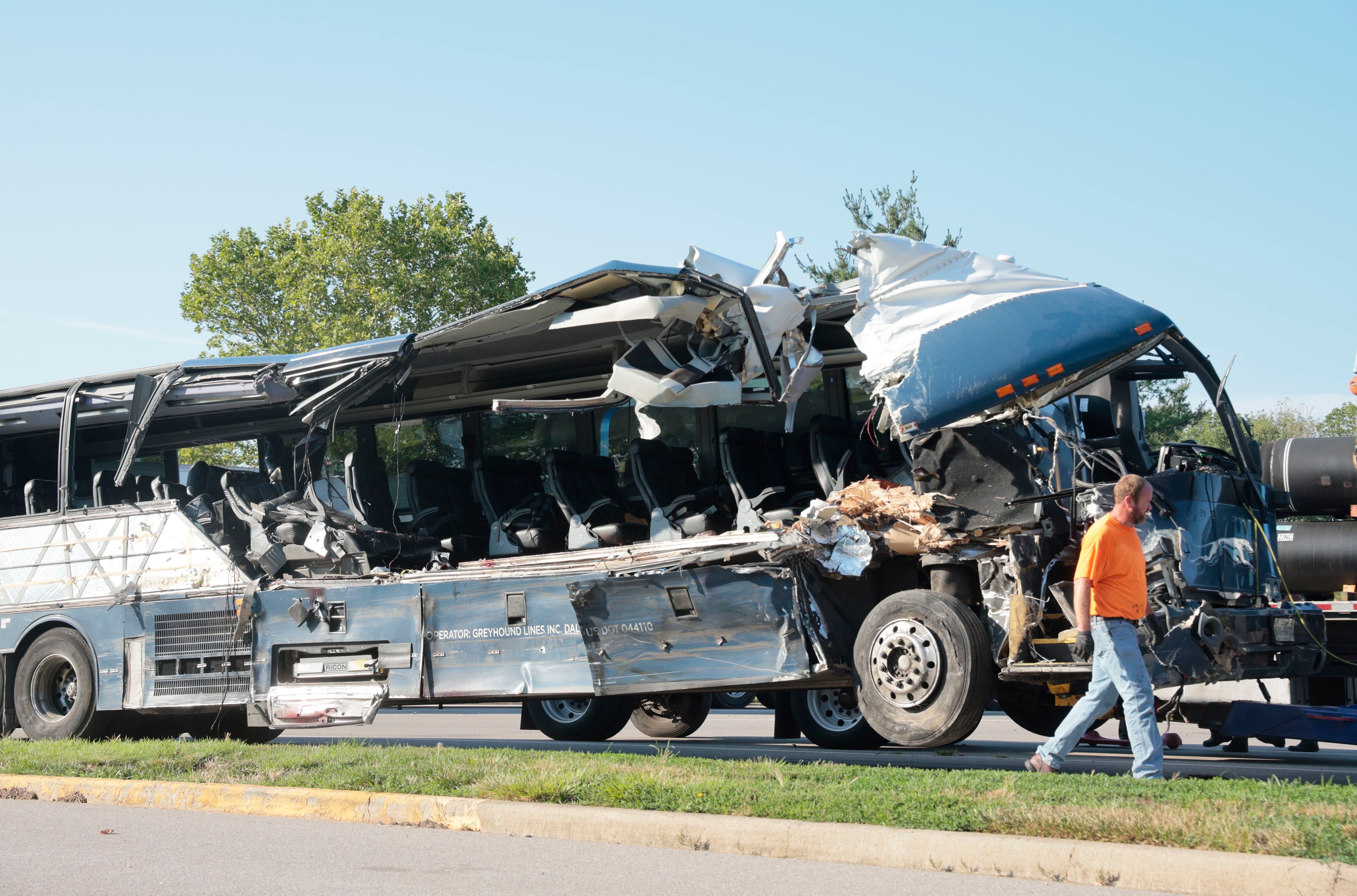 A worker helps clear the wreckage of a Greyhound bus that collided with tractor-trailers on the exit ramp to a rest area on westbound Interstate 70 in Highland, Ill., on Wednesday, July 12, 2023.