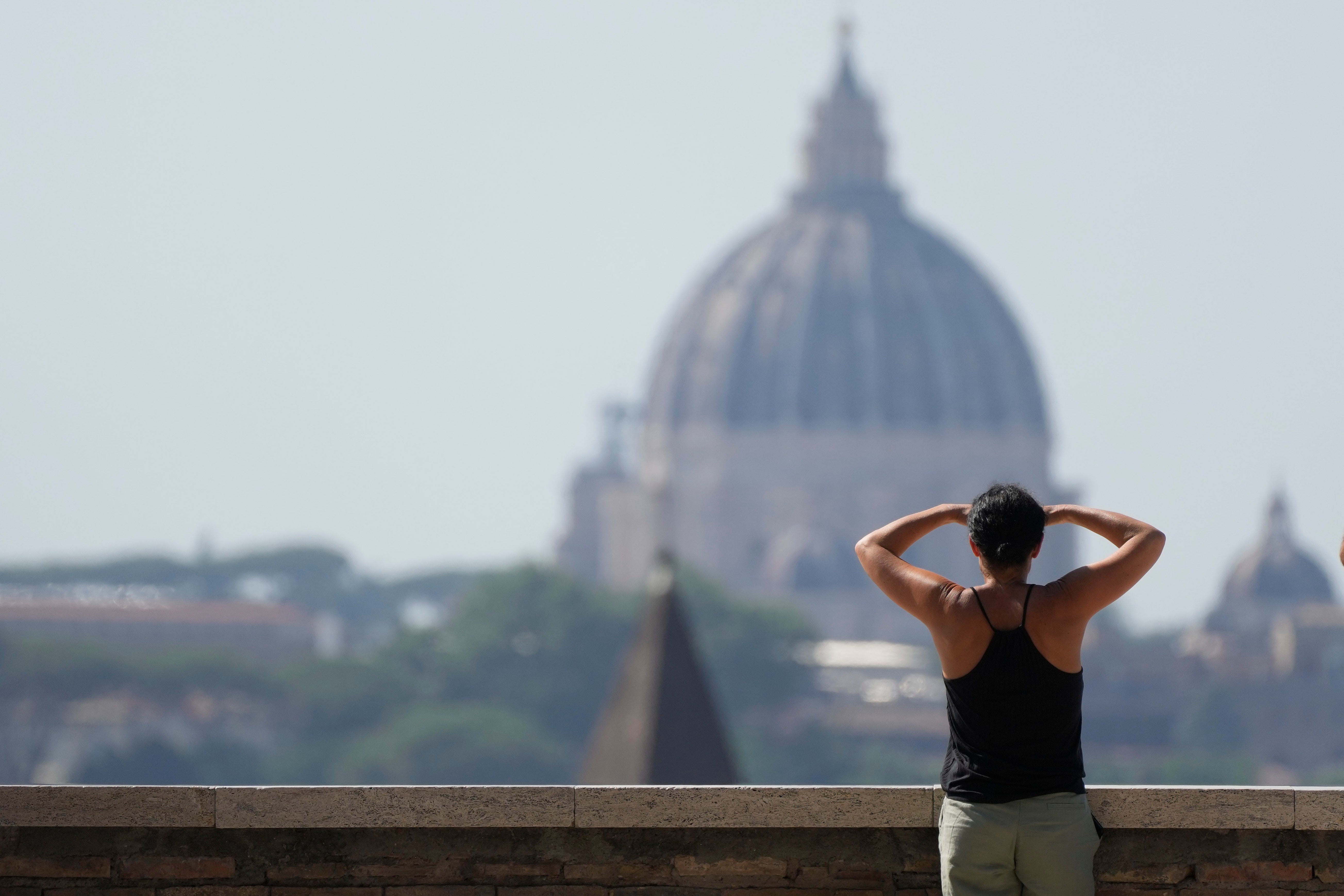 A woman admires the skyline filled by the St. Peter's Dome in Rome