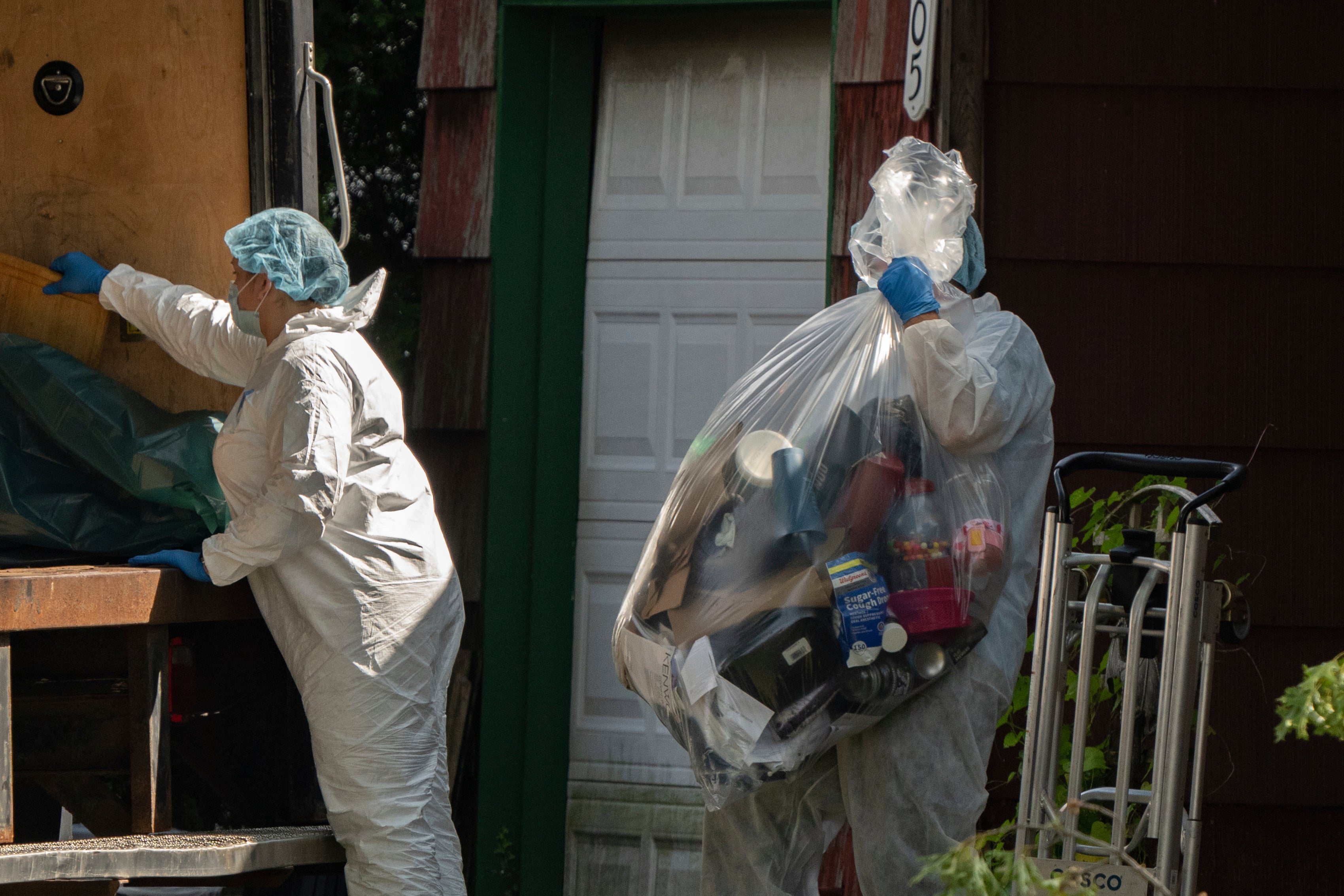 A crime laboratory officer moves a plastic bag of items as law enforcement searches the home of Rex Heuermann, Saturday, July 15, 2023, in Massapequa Park