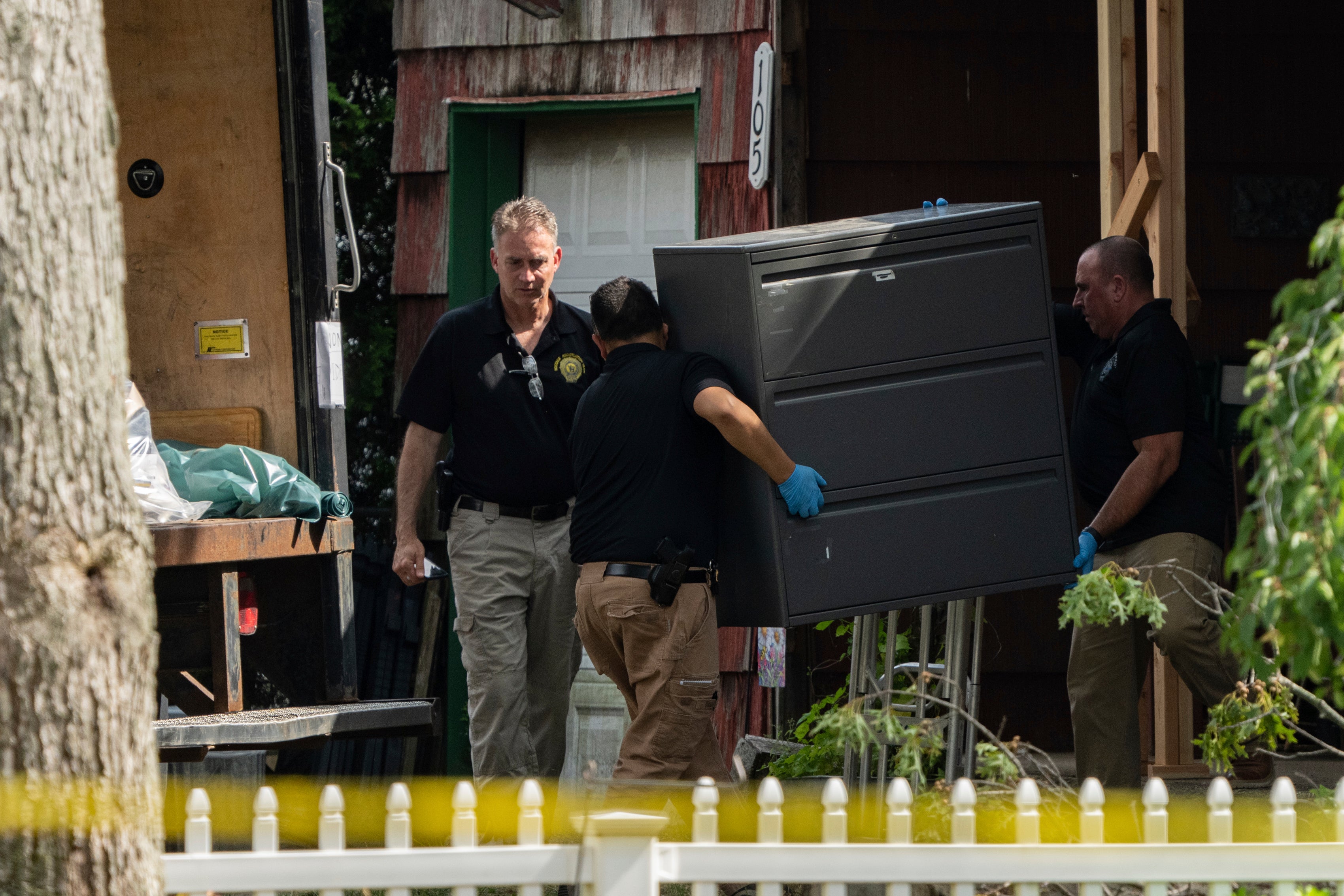 New York State police officers move a metal cabinet as law enforcement searches the home of Rex Heuermann, Saturday, July 15, 2023, in Massapequa Park, N.Y.