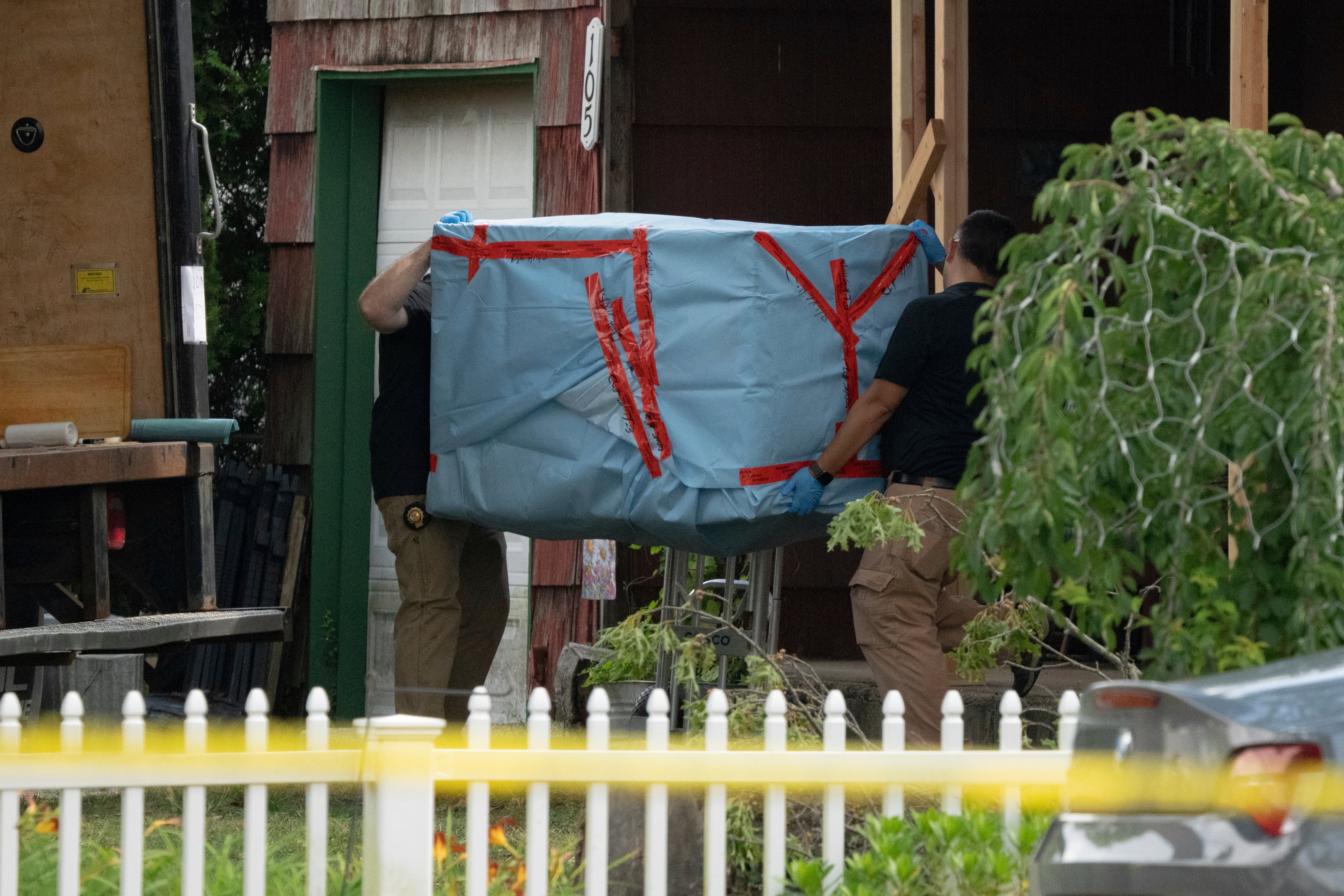 Oficiales de policía del estado de Nueva York llevan a cabo un objeto grande mientras la policía registra la casa de Rex Heuermann, el sábado 15 de julio de 2023, en Massapequa Park, N.Y.