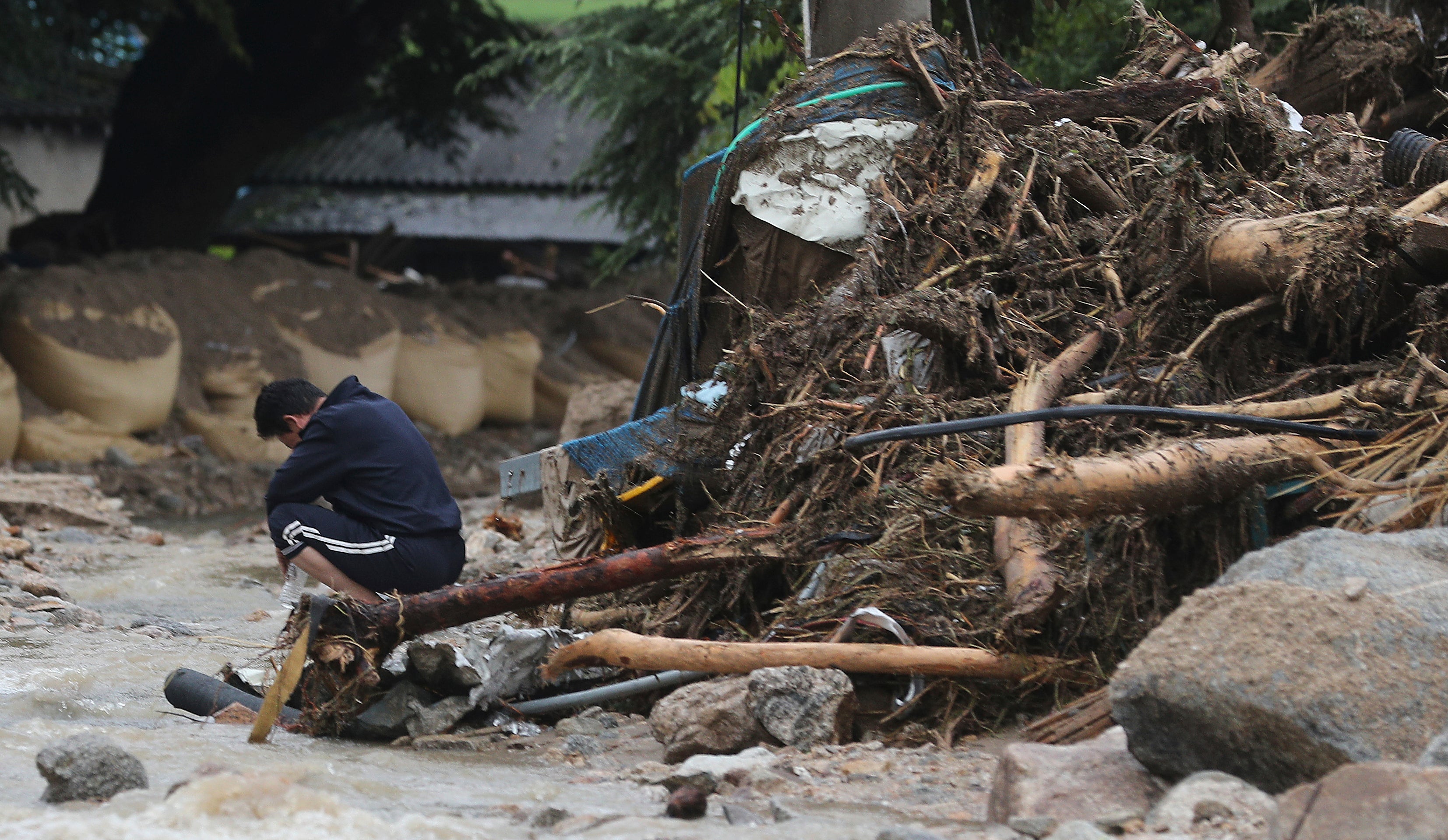A man sits next to his collapsed house after a landslide caused by heavy rain in Yecheon, South Korea