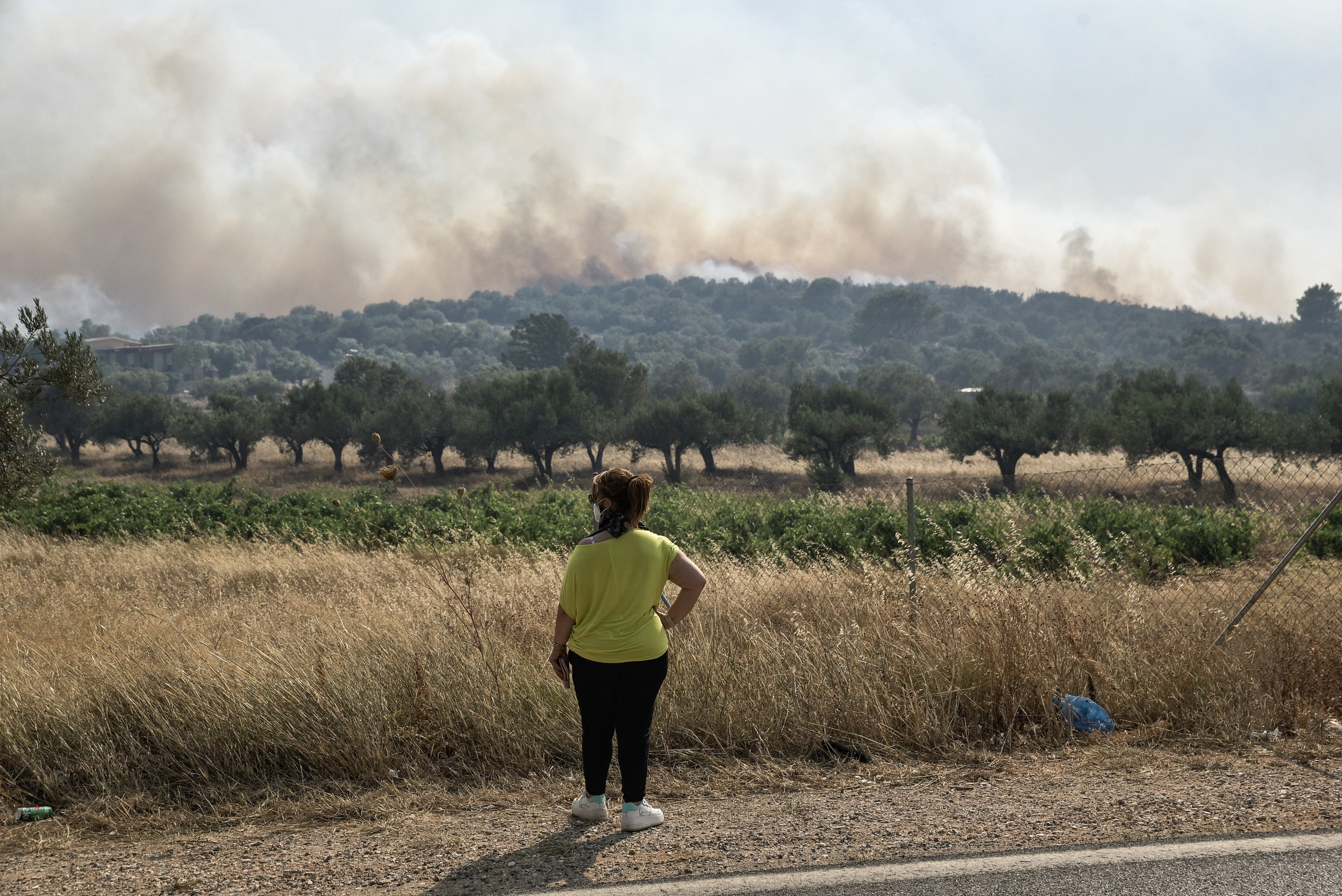 A woman looks at smoke from a wildfire some 50km southeast from the centre of Athens on July 17, 2023.