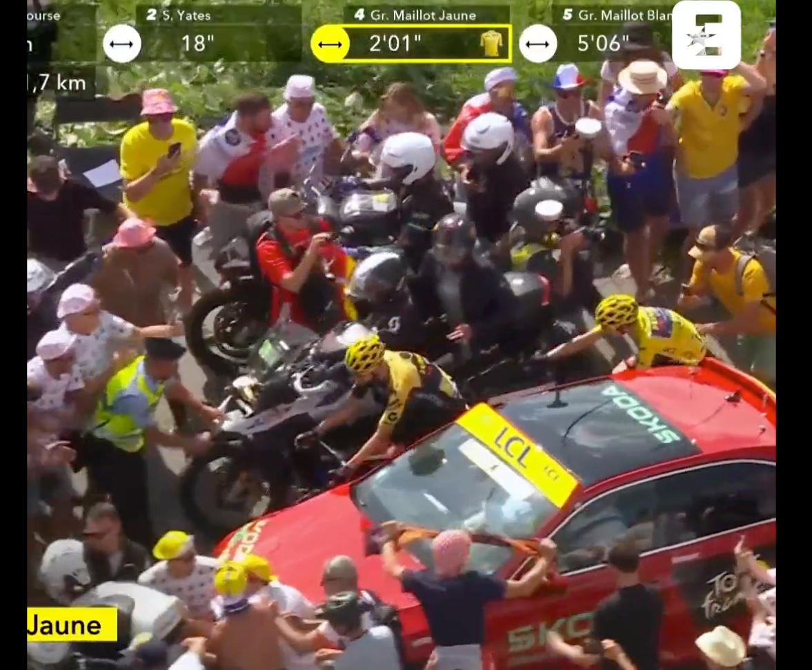 Jonas Vingegeaard attempts to pass between a motorbike and car on the mountain