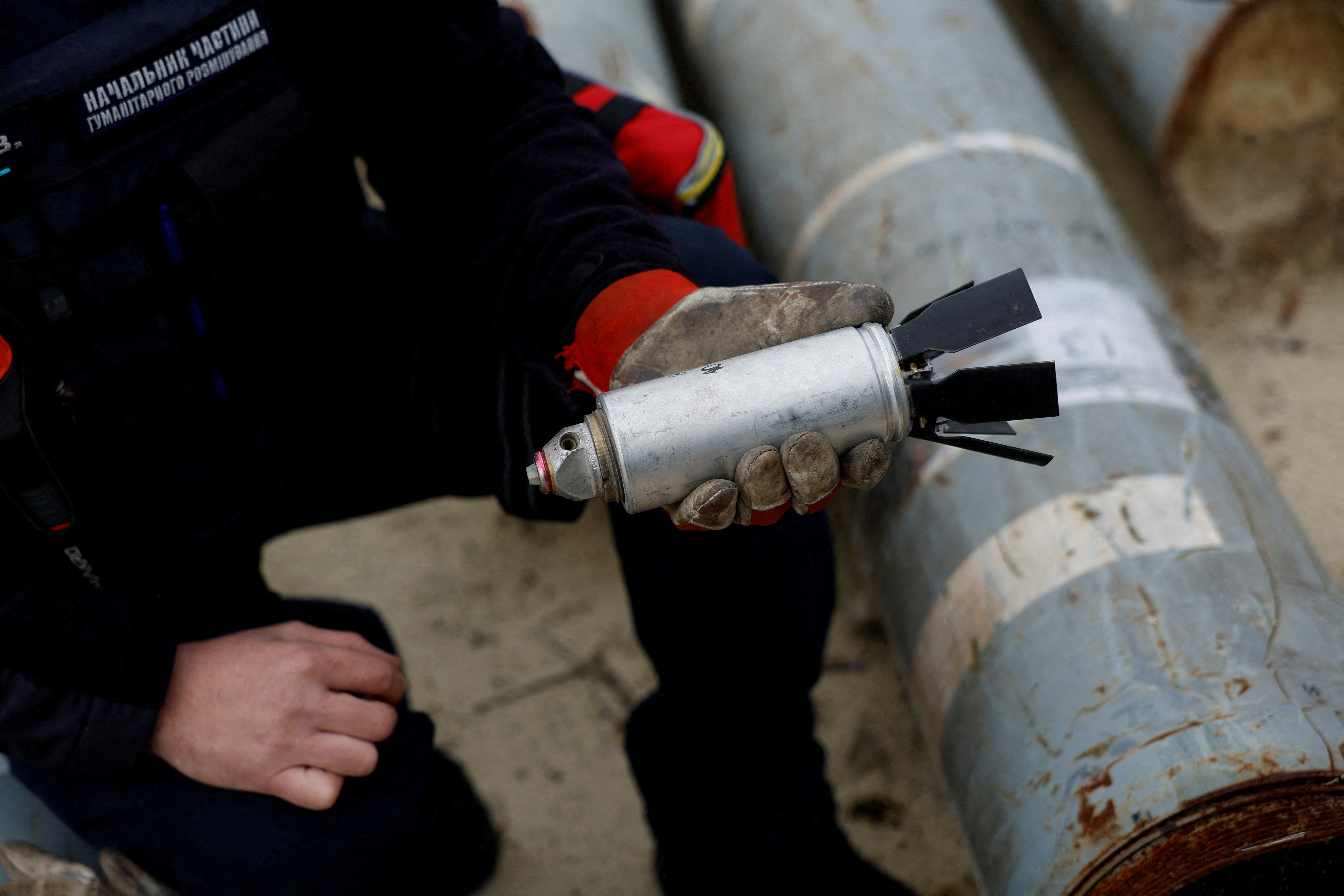 Ukrainian military serviceman holds a defused cluster bomb from an MSLR missile