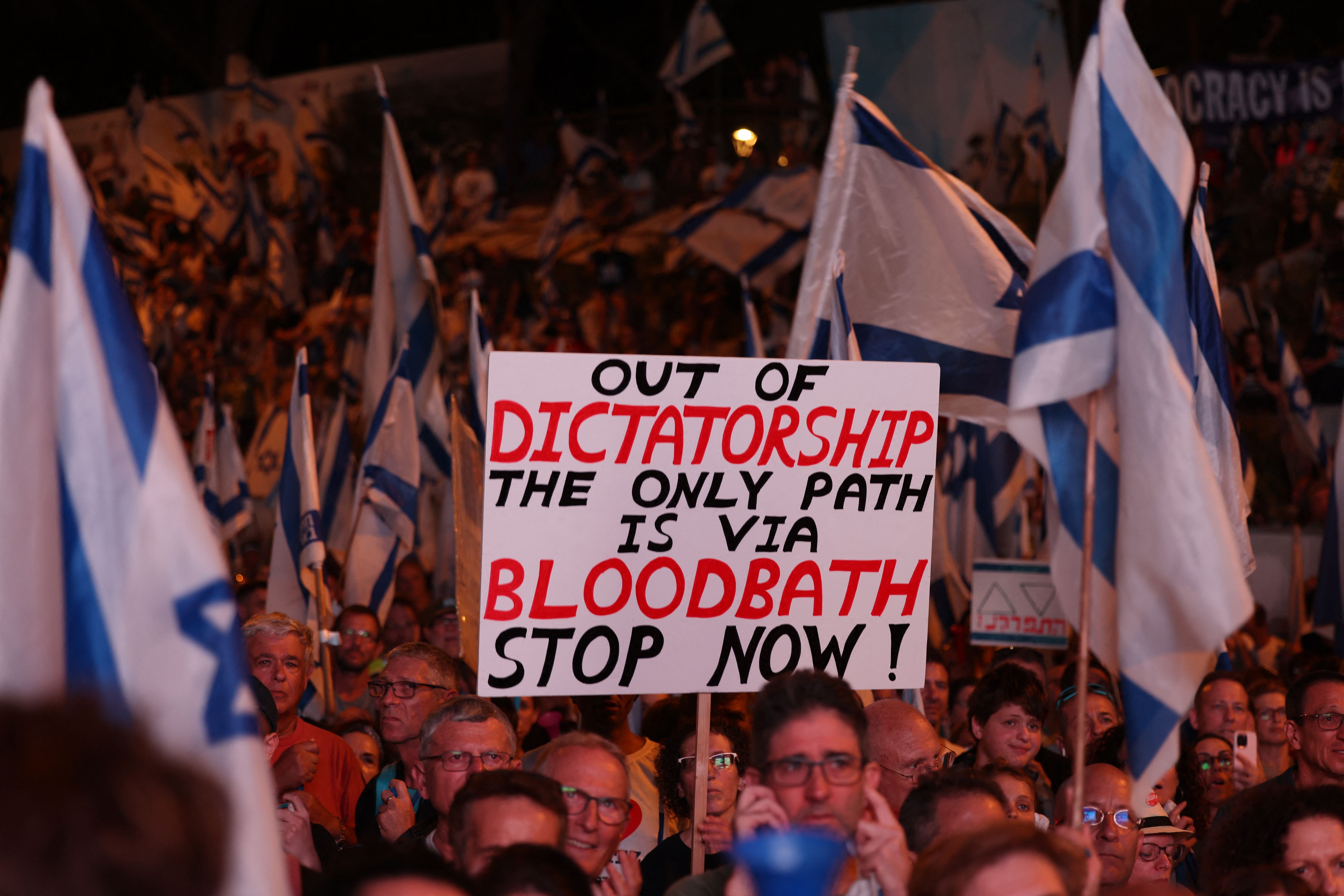 Demonstrators raise placards as they march in Jerusalem on July 22, 2023, during a multi-day march that started in Tel Aviv to protest the government’s judicial overhaul bill ahead of a vote in the parliament