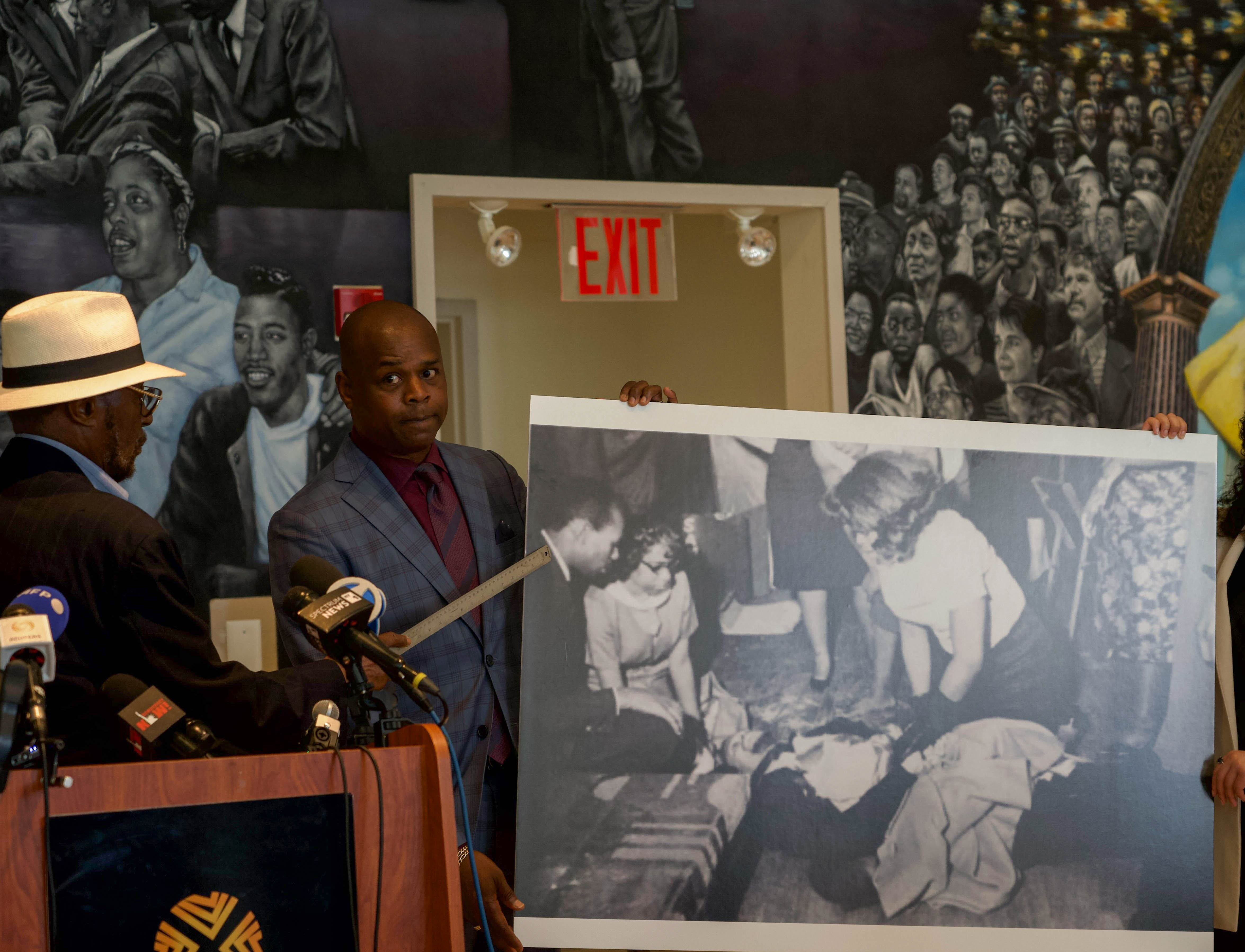 Mustafa Hassan points to a photo of himself next to Malcolm X after he was shot