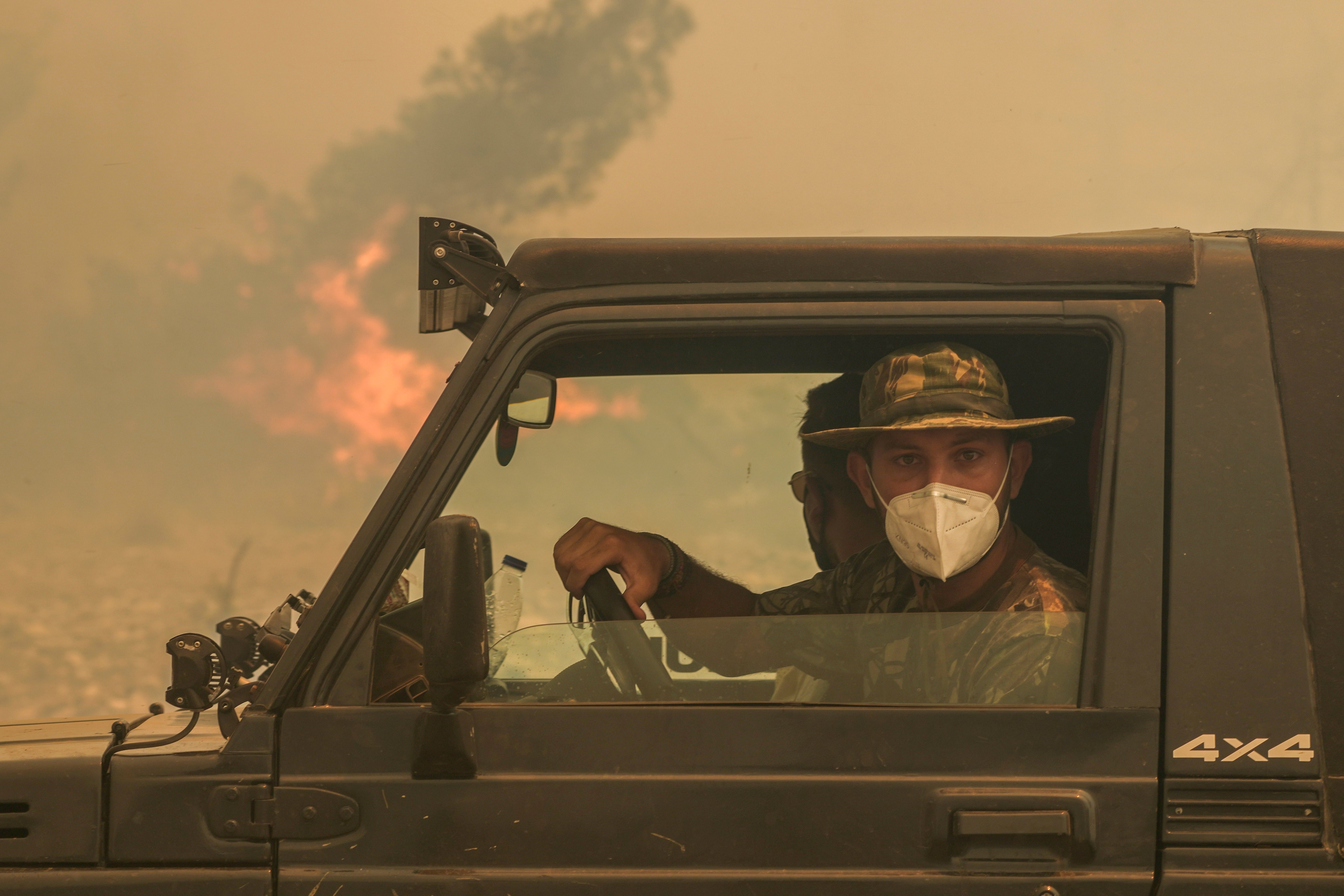 Military personnel look on as the fires continue to burn