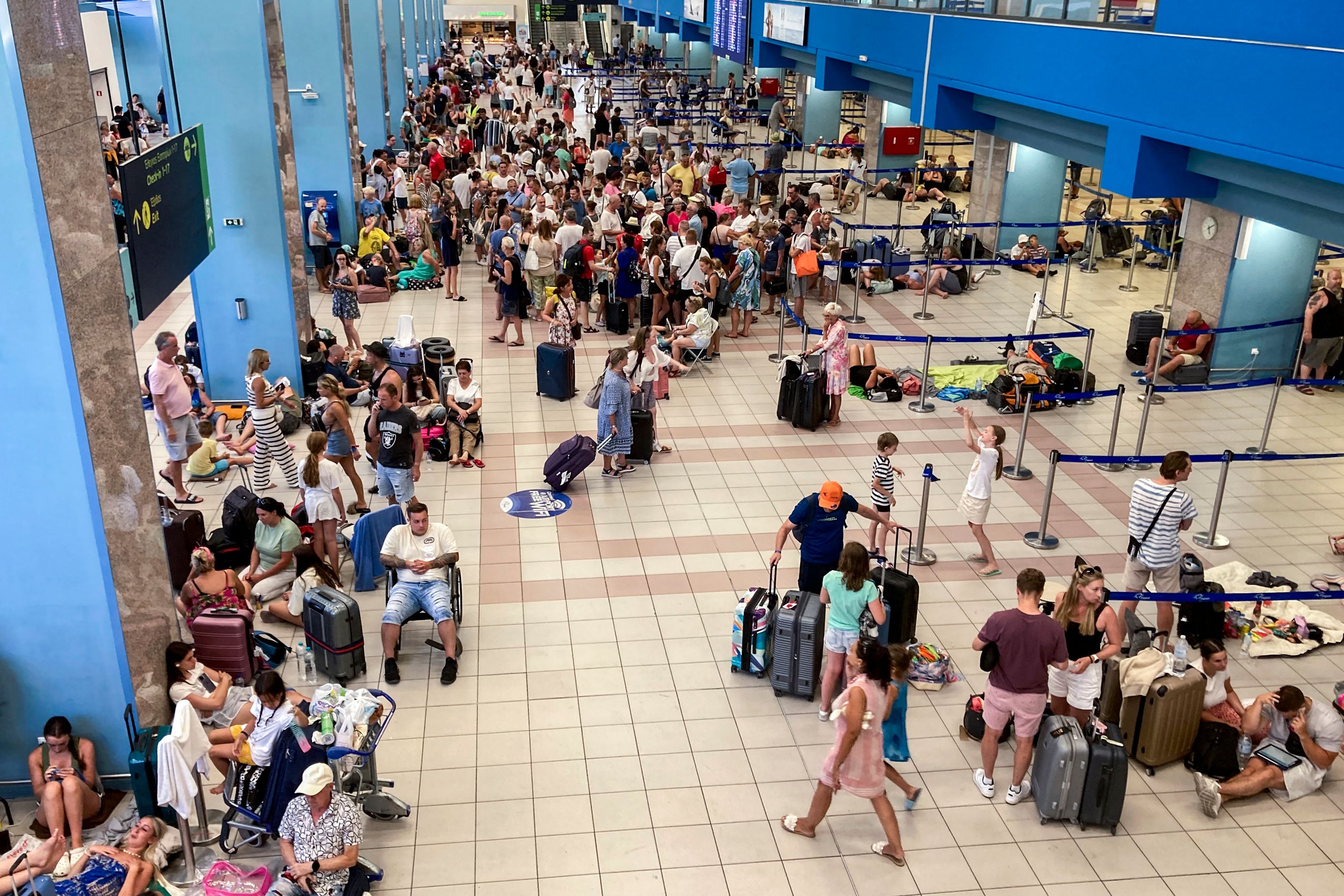 Tourists wait in the airport’s departure hall during evacuations on the Greek island of Rhodes on 23 July