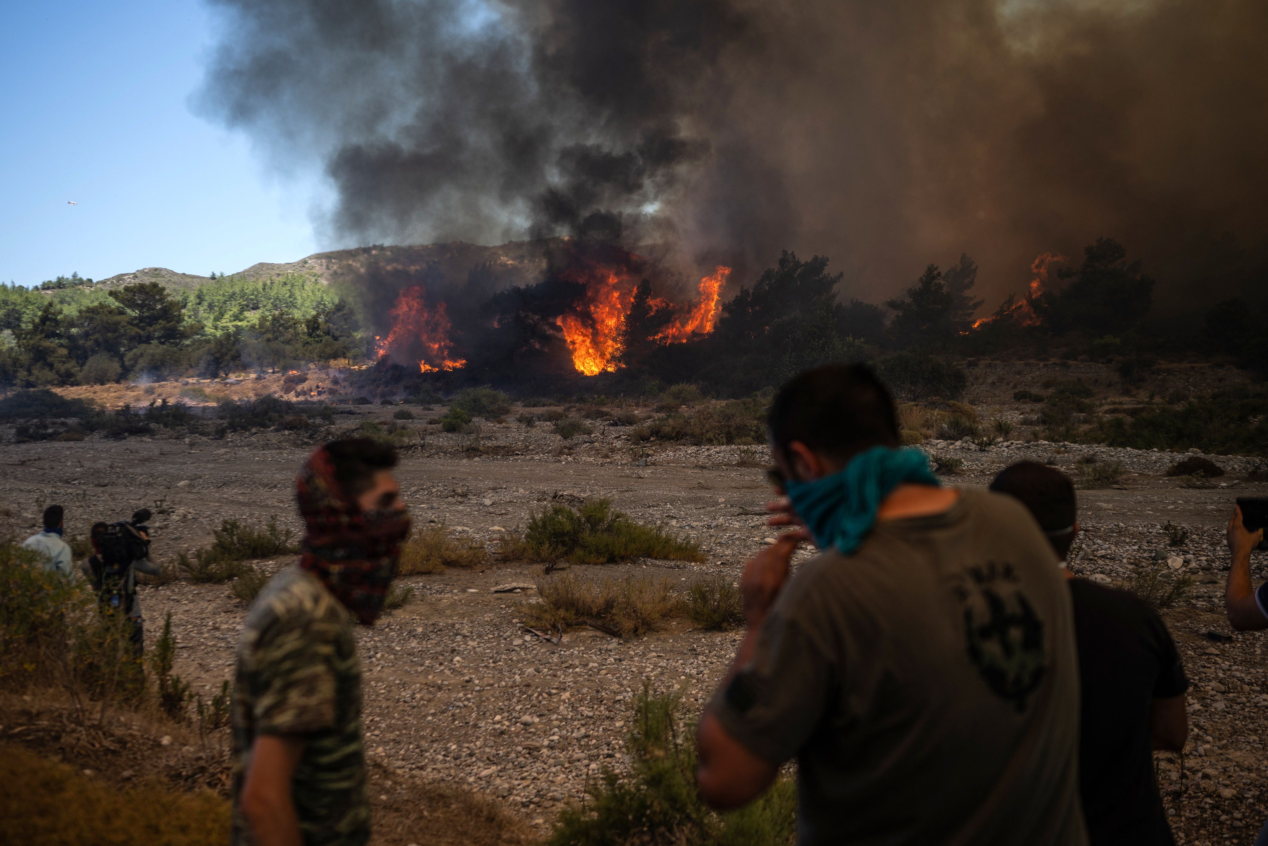 Locals watch on as the fire approaches the village of Vati on Tuesday