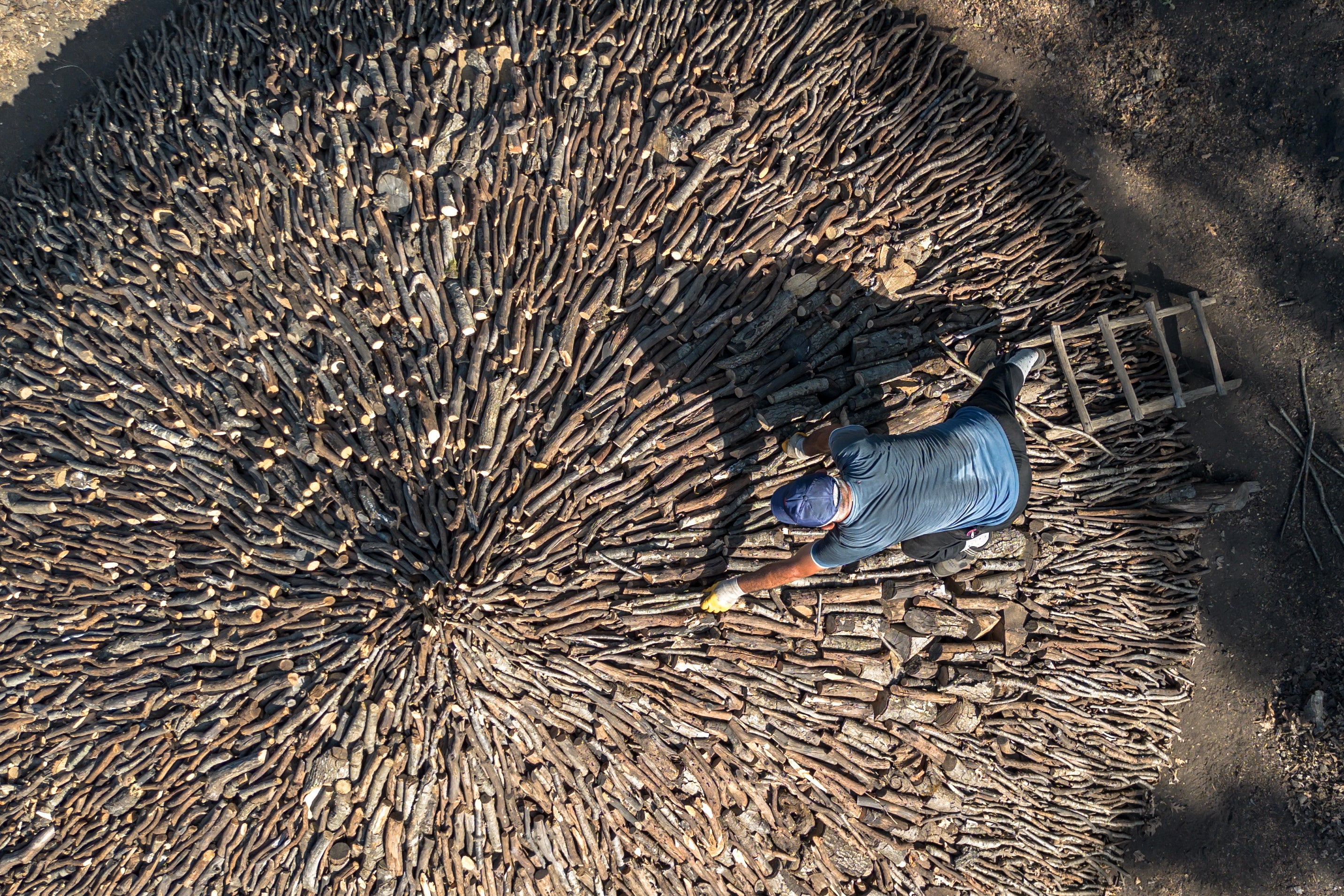 A photo taken with a drone shows a charcoal worker preparing a pile of oak wood to burn as part of the production of the handcrafted charcoal in Sile district of Istanbul