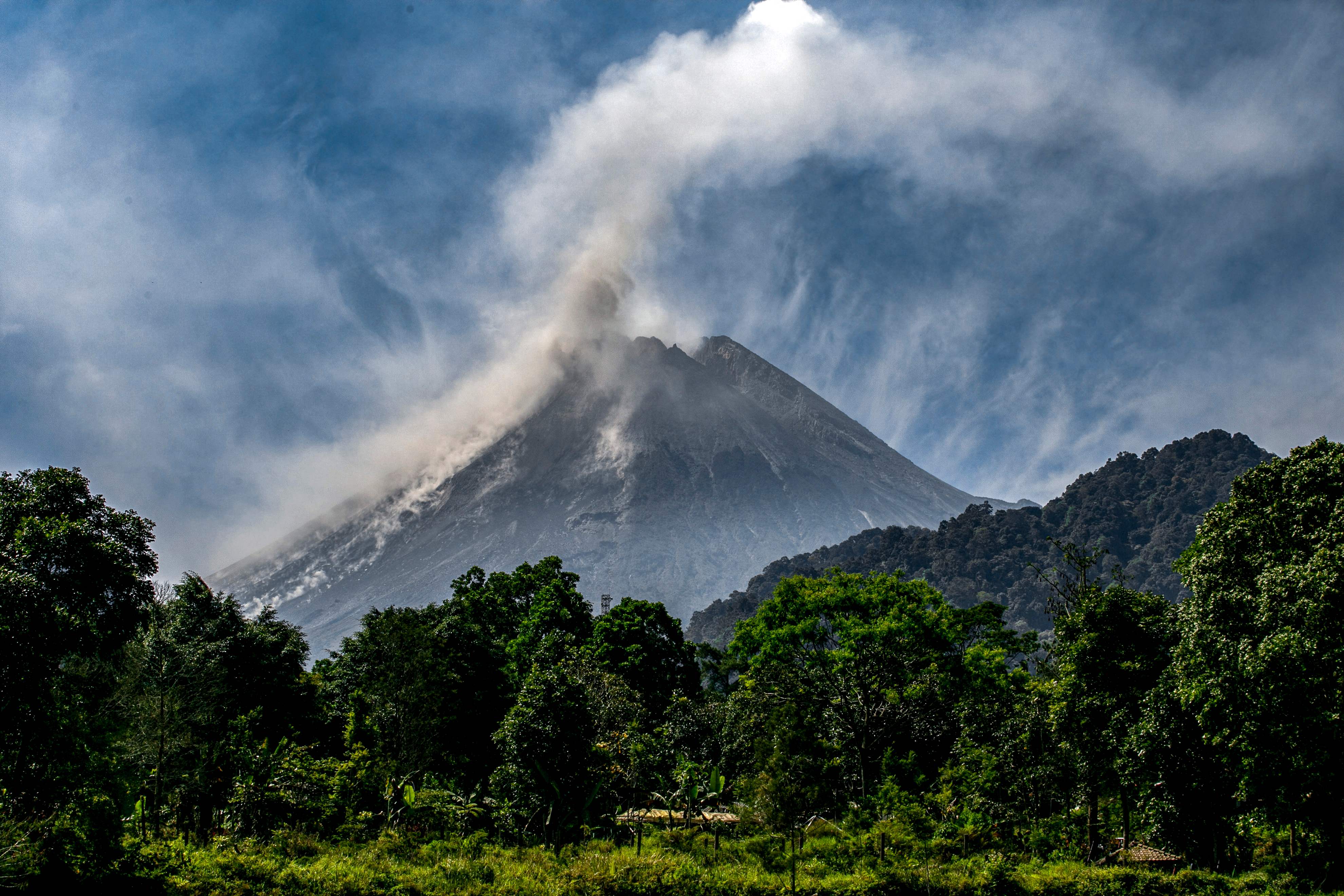 Mount Merapi billows smoke into the air and lava onto its slopes during its eruption as seen from Hargobinangun village, in Sleman