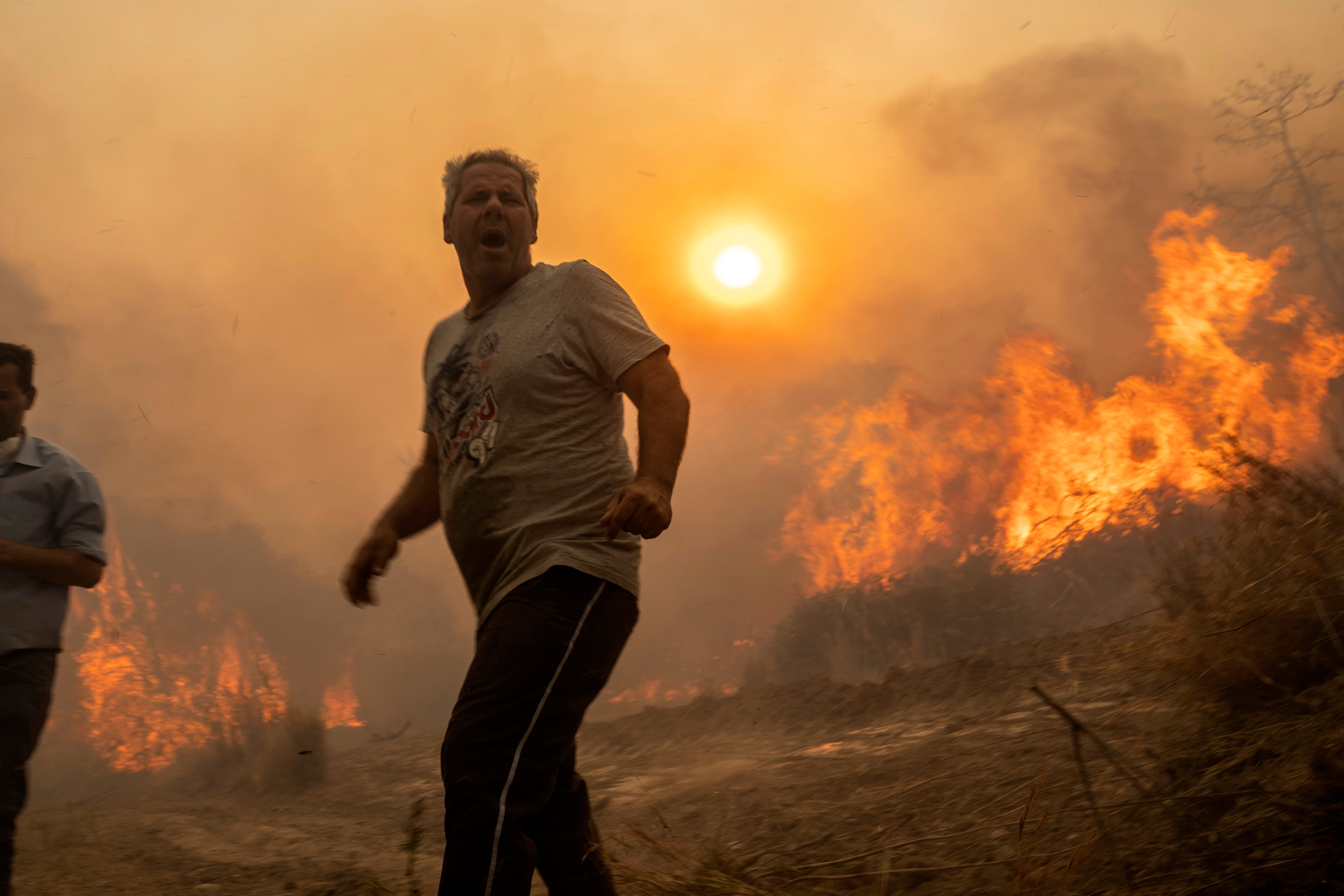 A local reacts as the flames burn trees in Gennadi village, on the Aegean Sea island of Rhodes