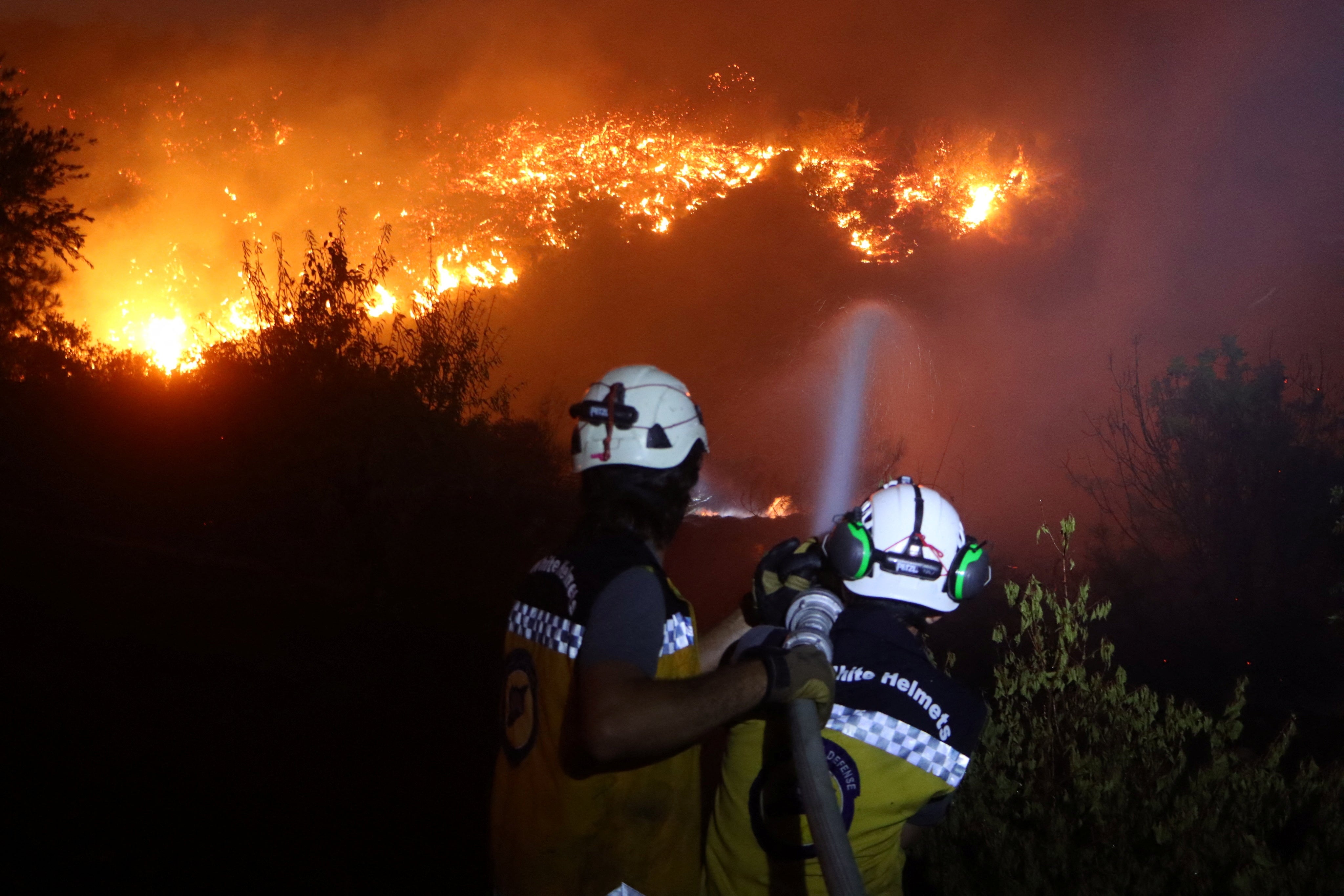 White Helmets volunteers extinguish a wildfire in the Deir Othman village of Idlib, Syria