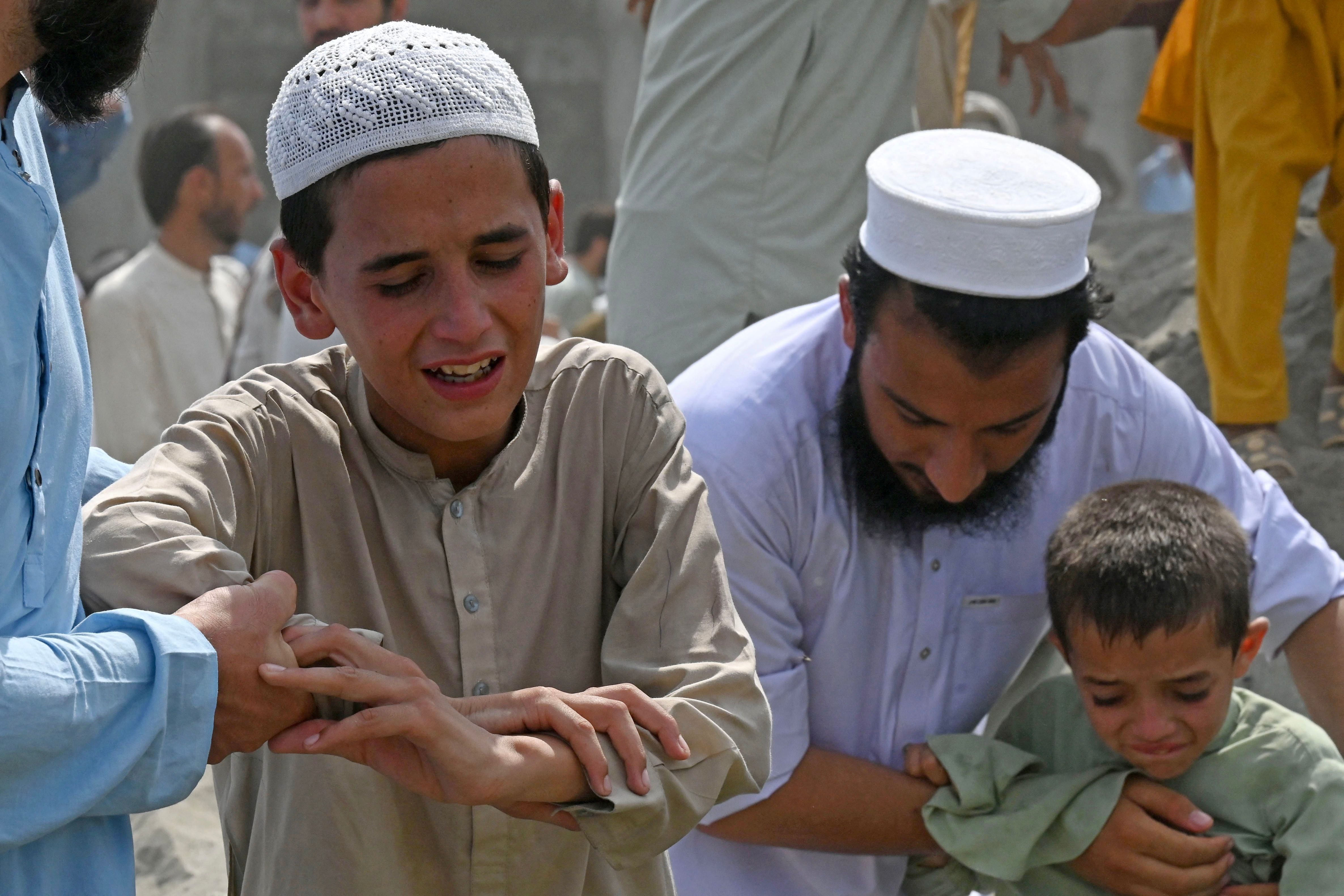 Boys weep the death of their family member, a day after bomb blast in Bajaur district