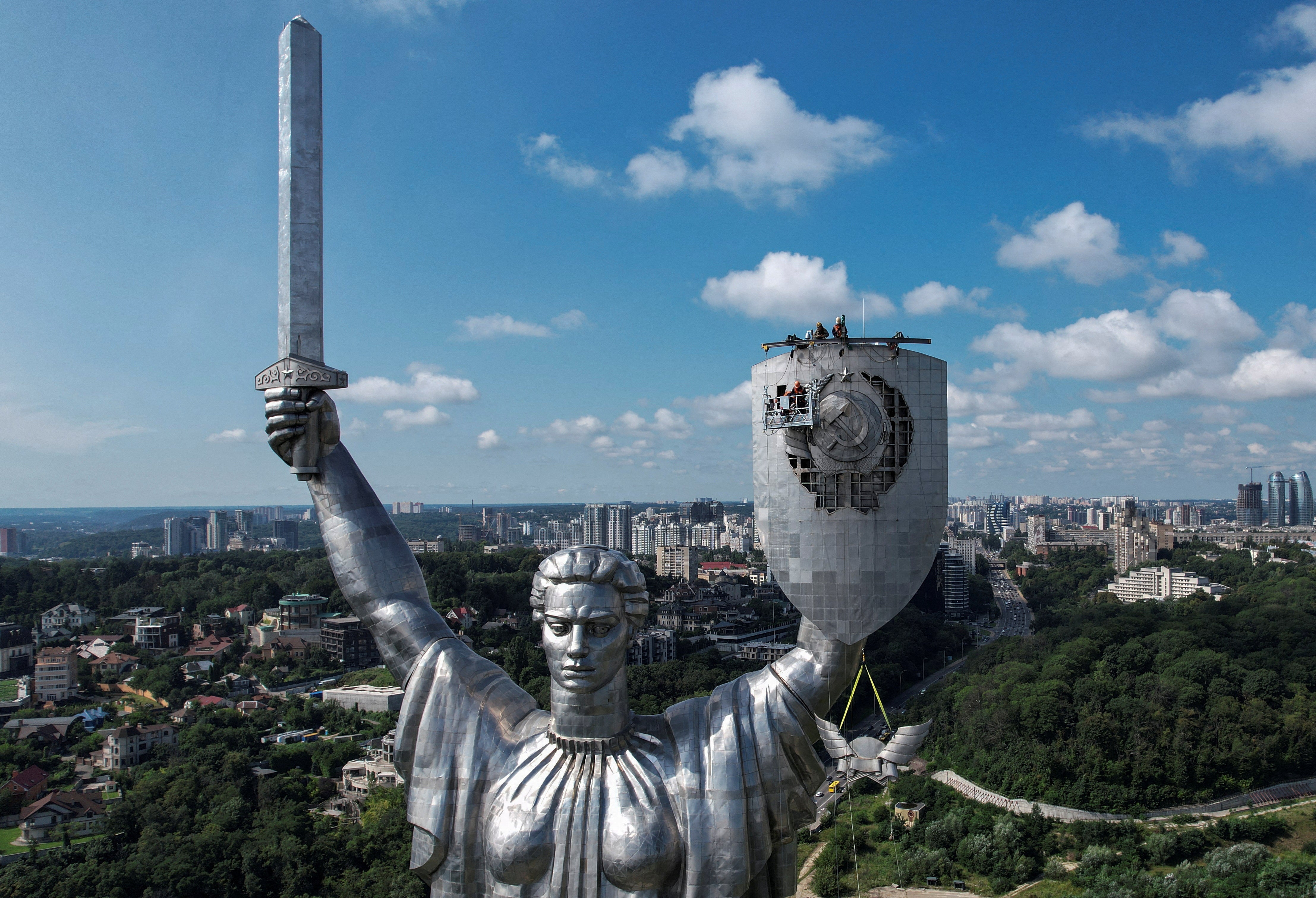 Workers dismount a Soviet emblem from the shield of the ‘Motherland’ monument, at a compound of the World War II museum in Kyiv, Ukraine