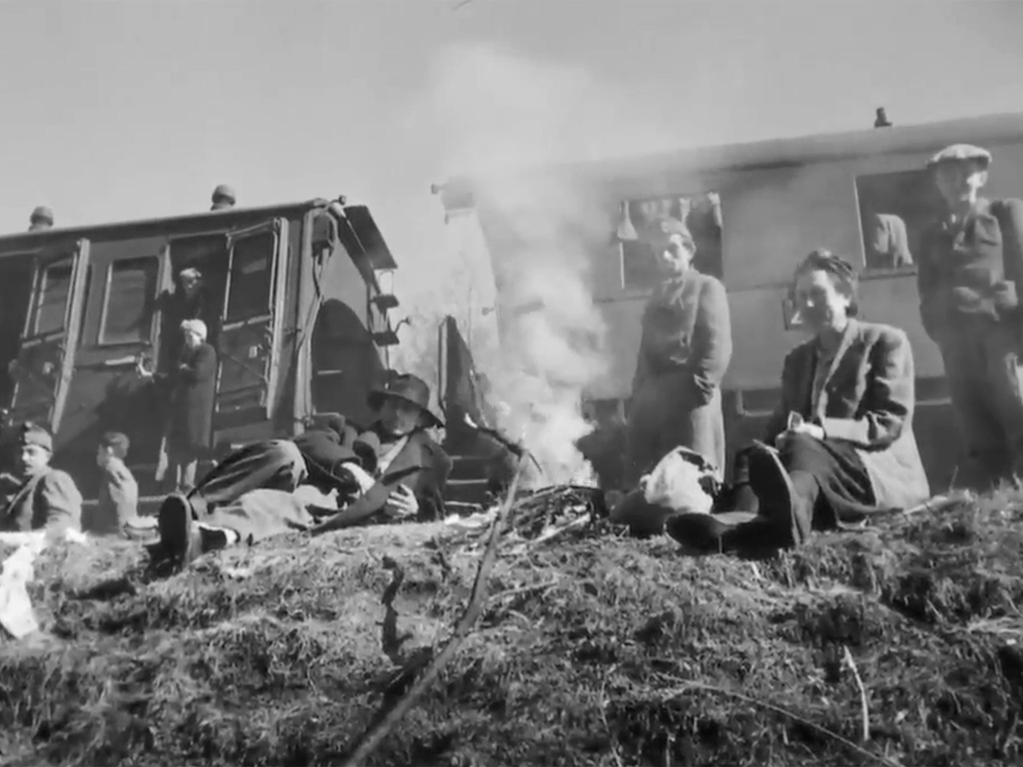 Prisoners sit waiting on the banks. The presence of a few fires suggests the air is anything but warm