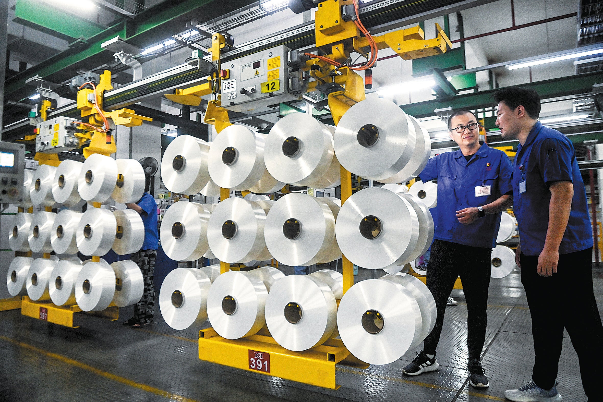 Employees work on the production line of a chemical fibre company in Jiaxing, Zhejiang province, in June