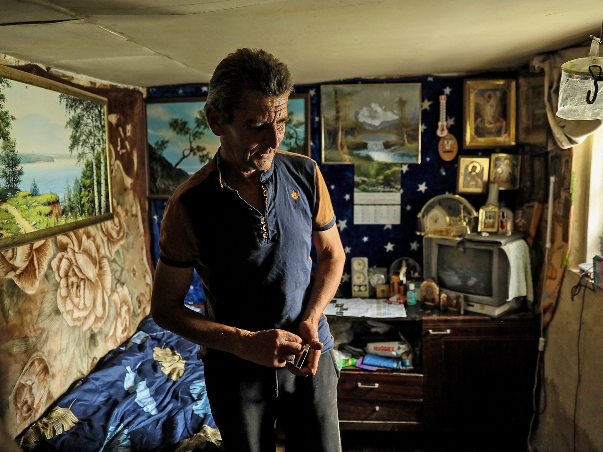 Mykola, 58, stands in his house in Bohorodychne village