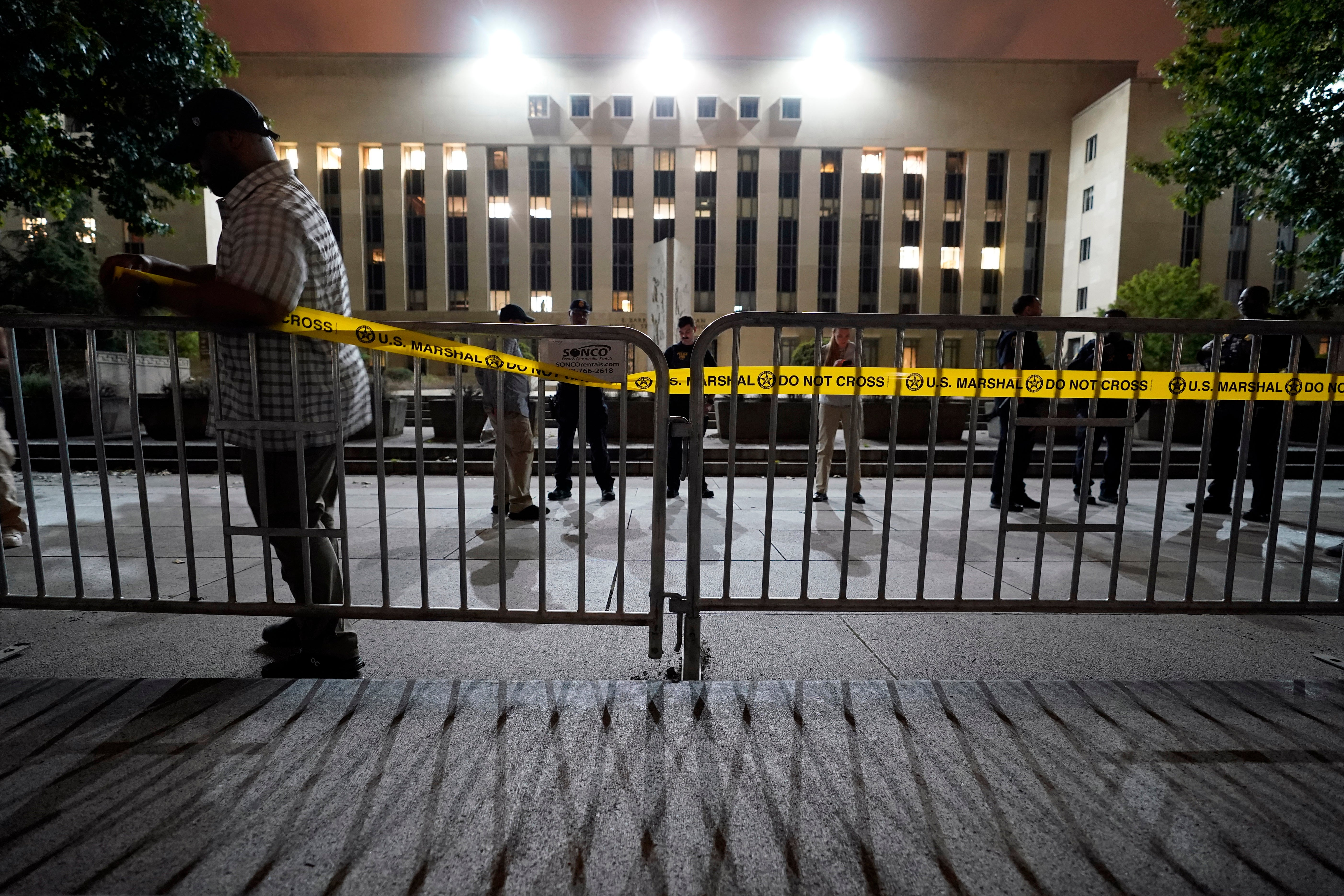 Workers put up barricades and secure the area outside the E. Barrett Prettyman U.S. Federal Courthouse