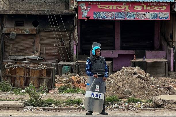 A Rapid Action Force (RAF) personnel stands beside closed shops during patrolling following communal clashes in Nuh in India’s Haryana state on 2 August 2023