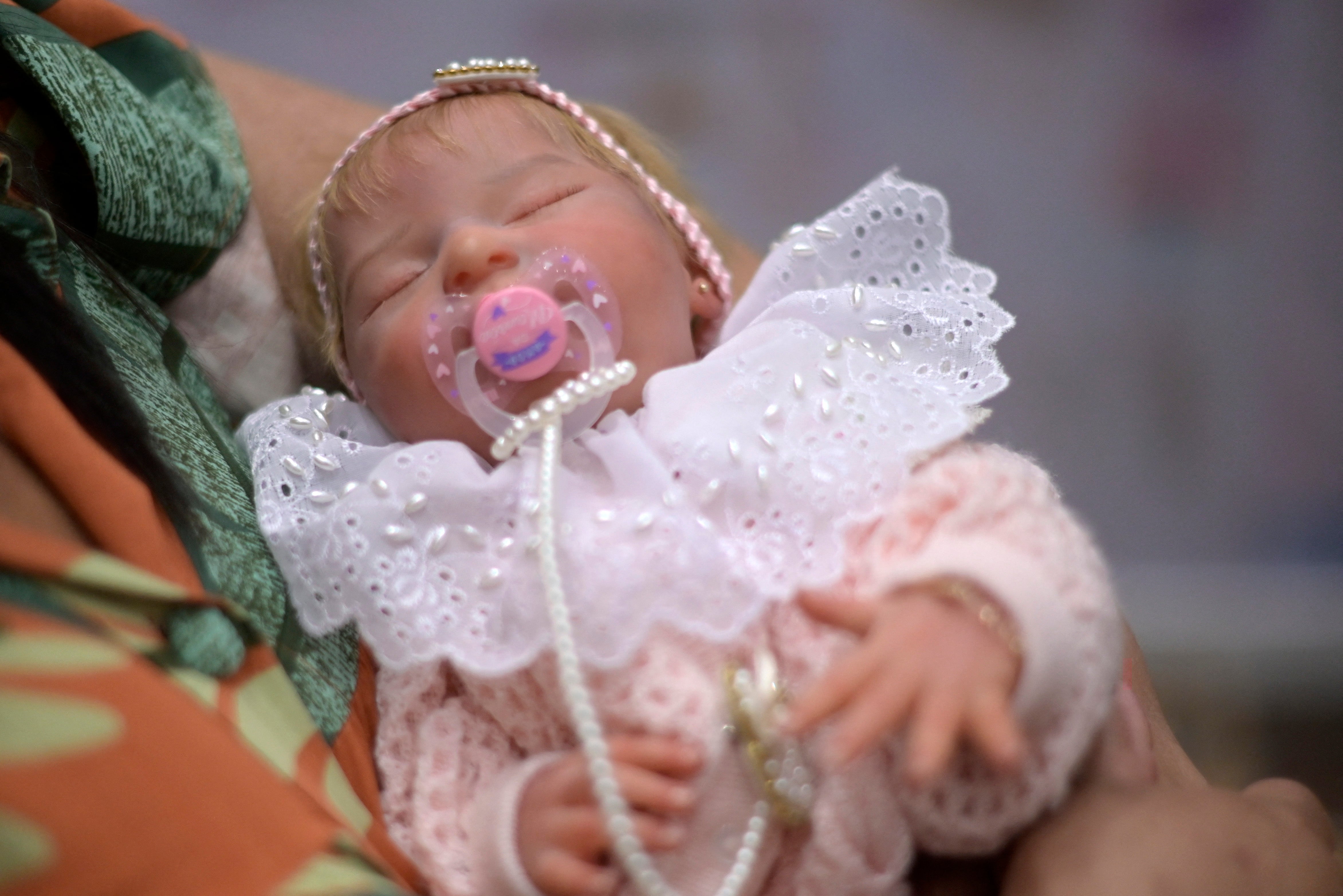 A woman holds a super realistic doll during a gathering of collectors and producers in a mall in Belo Horizonte, Minas Gerais state, Brazil on November 6, 2022