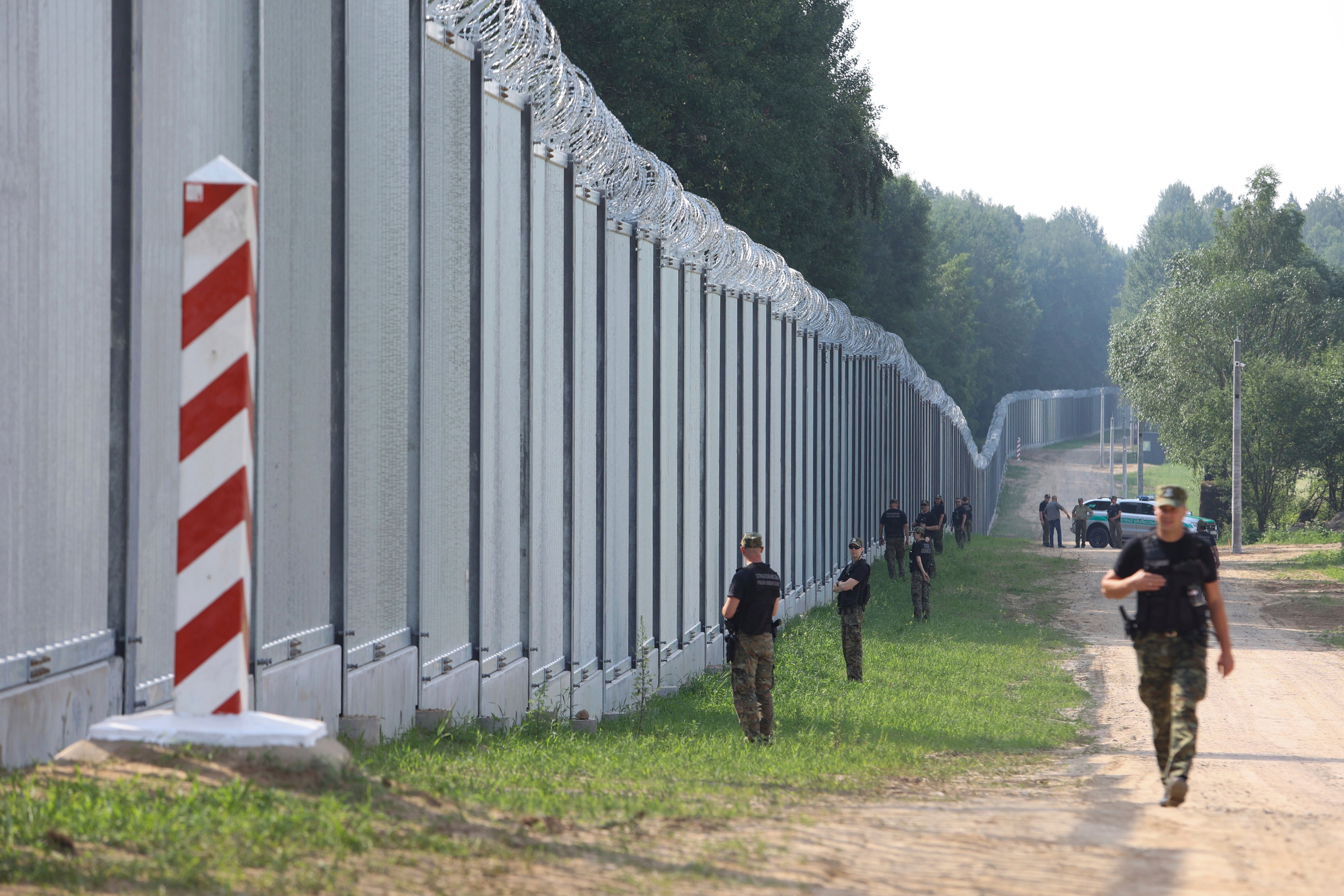 Polish border guards patrol the area of a newly built metal wall on the border between Poland and Belarus