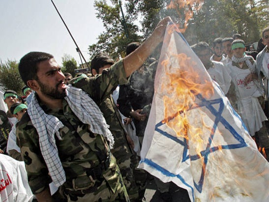 A member of Iran’s Revolutionary Guards burns an Israeli flag during a demonstration in 2006