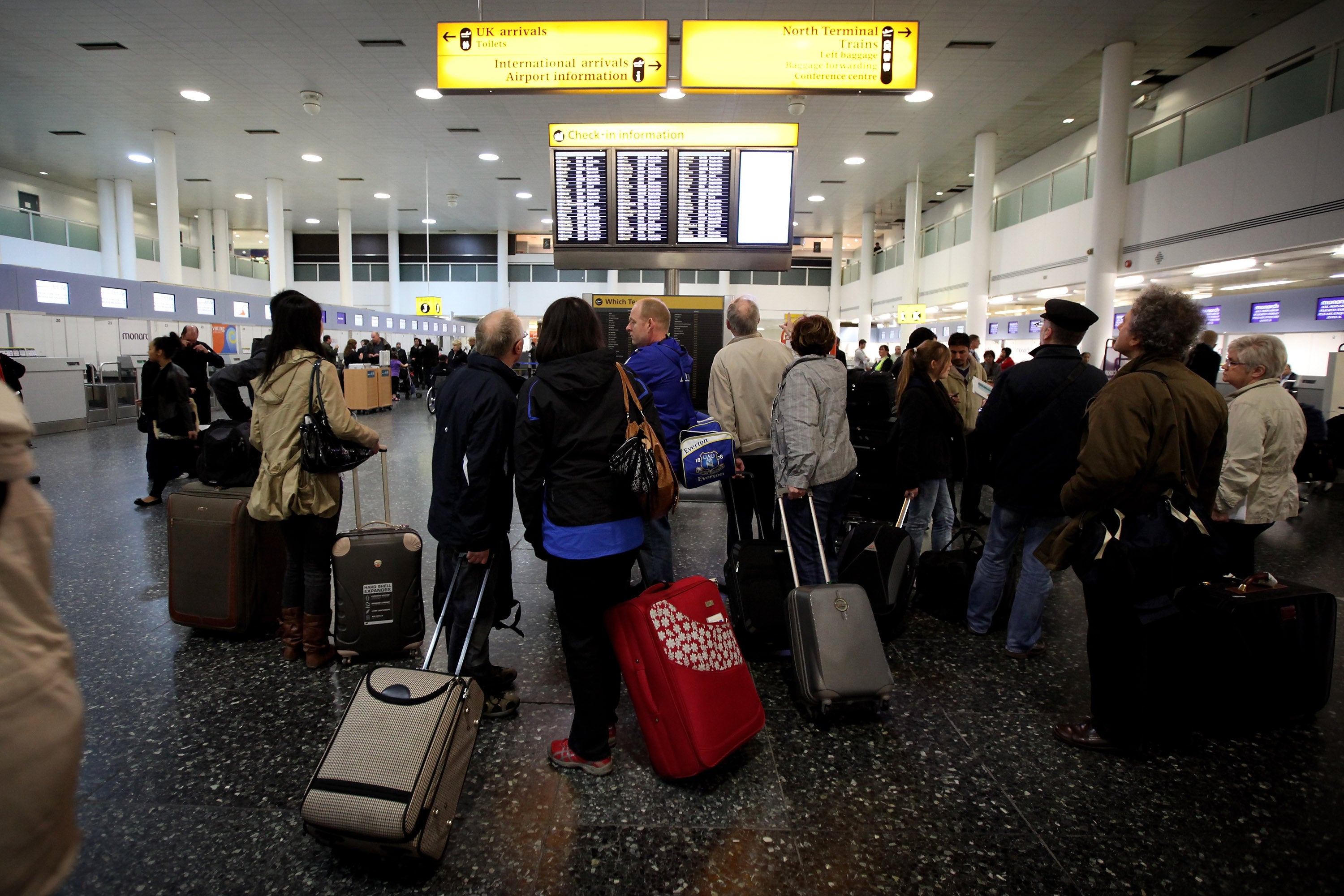 Going nowhere: holidaymakers look for news about their grounded flights on an information board at Gatwick airport