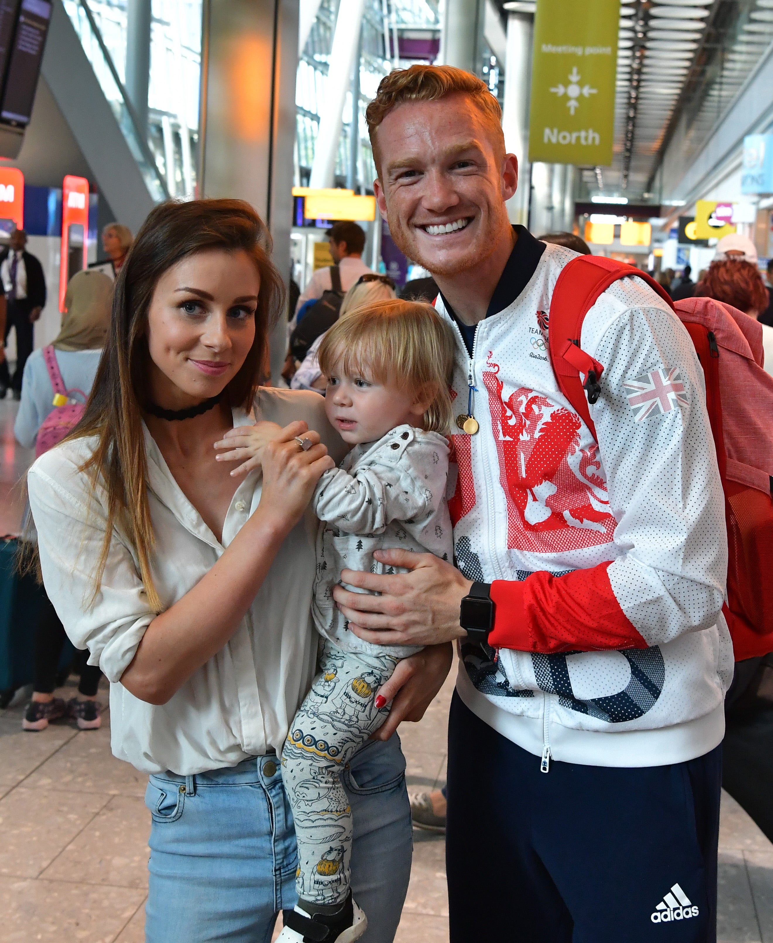 Greg Rutherford poses for a photograph with his partner Susie Verrill and son Milo after arriving on a British Airways flight from Rio de Janeiro to London Heathrow Airport Terminal 5 on August 17, 2016