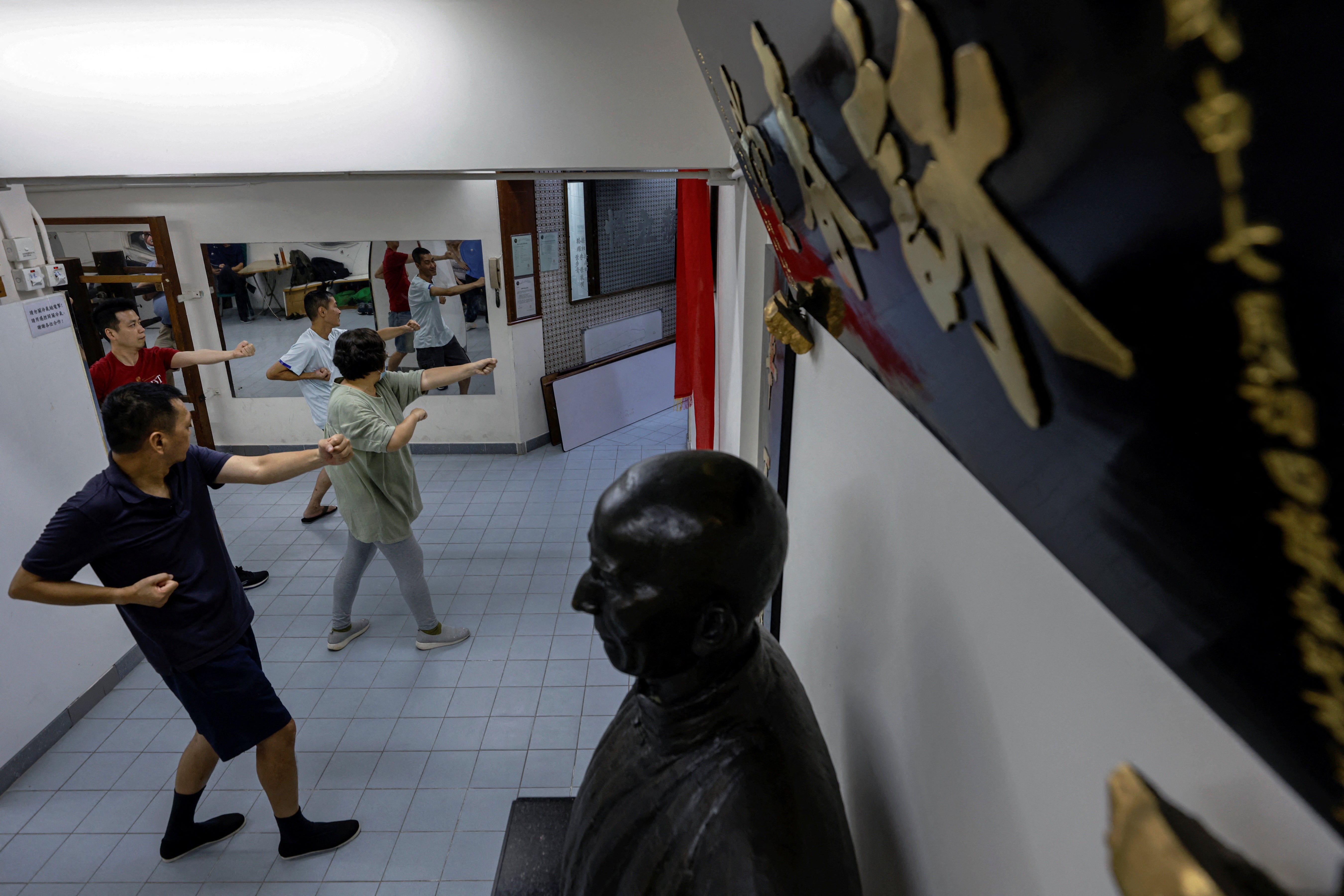 Students practice nearby grandmaster Ip Man’s bronze statue, at a Wing Chun school